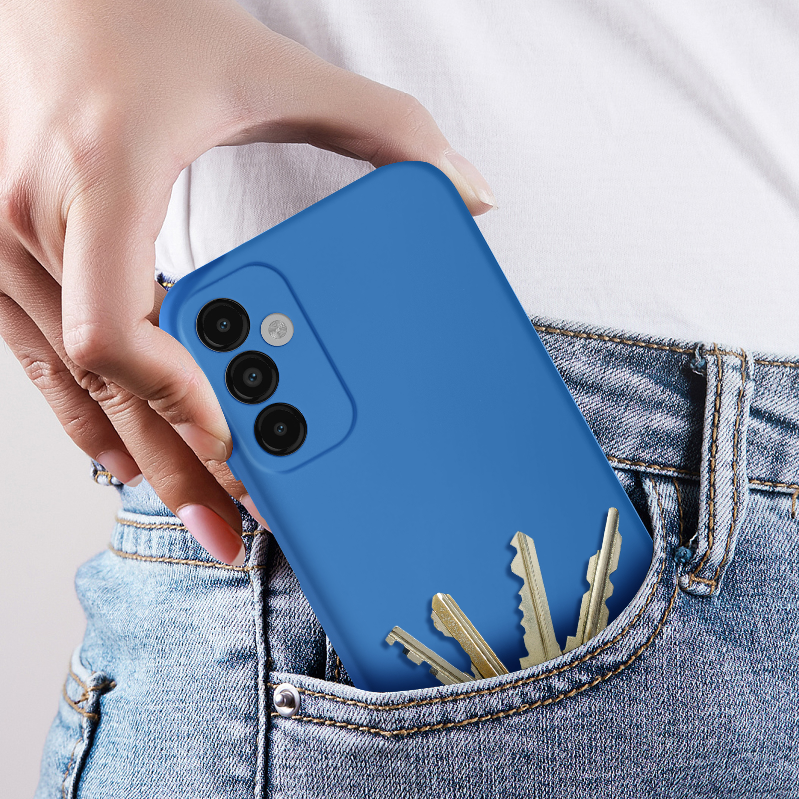 Una mano in tasca a un jeans, che tiene una custodia blu per telefono con chiavi.