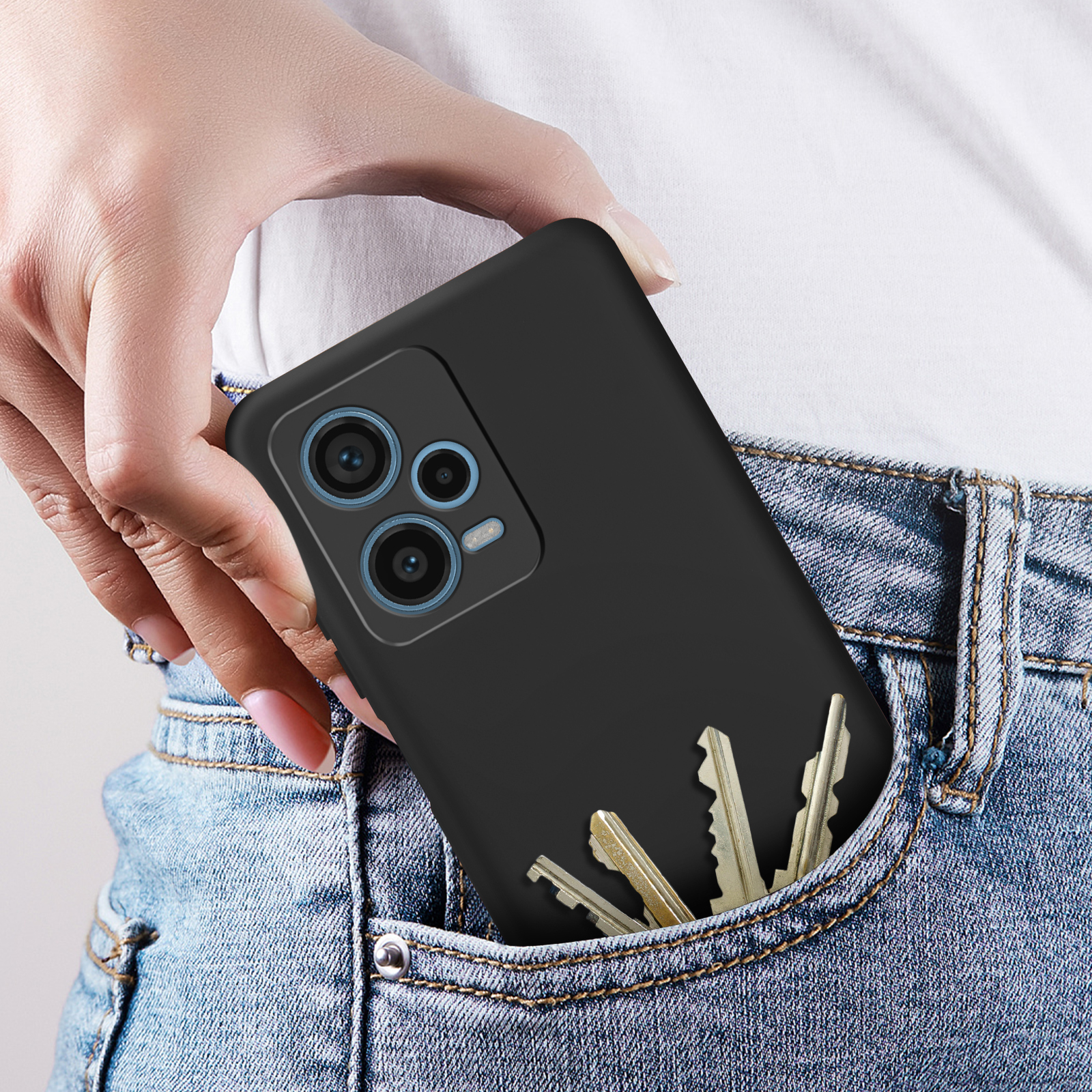 Una custodia nera per telefono con chiavi in una tasca di jeans, tenuta da una persona.