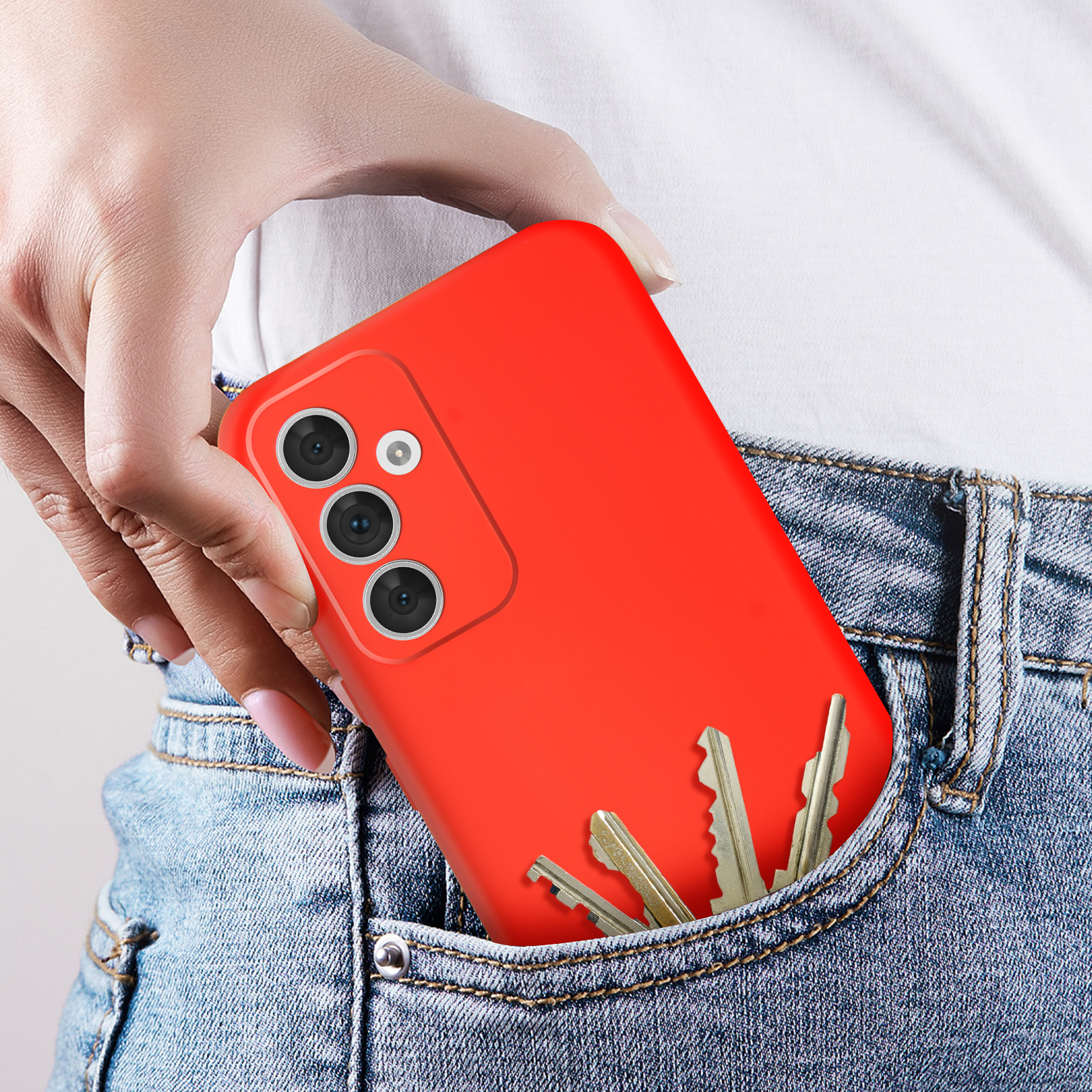 Mano nella tasca dei jeans con chiavi e una custodia rossa per telefono.