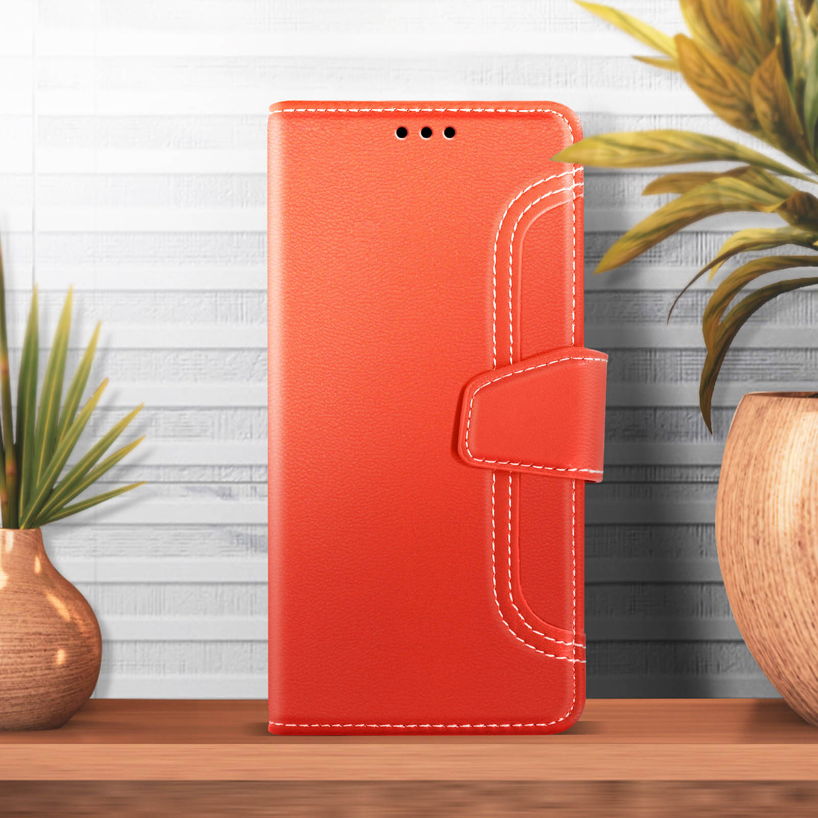 Una custodia per telefono rossa in piedi su una superficie di legno. La custodia è chiusa, con cuciture bianche.
