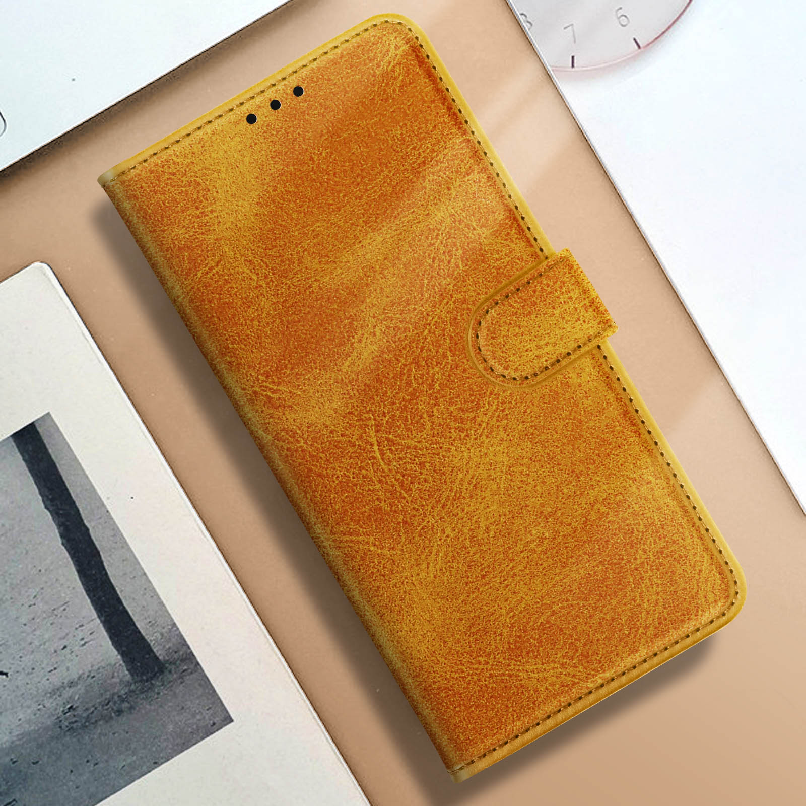 Custodia per telefono color senape con coperchio chiuso. Su una superficie chiara.