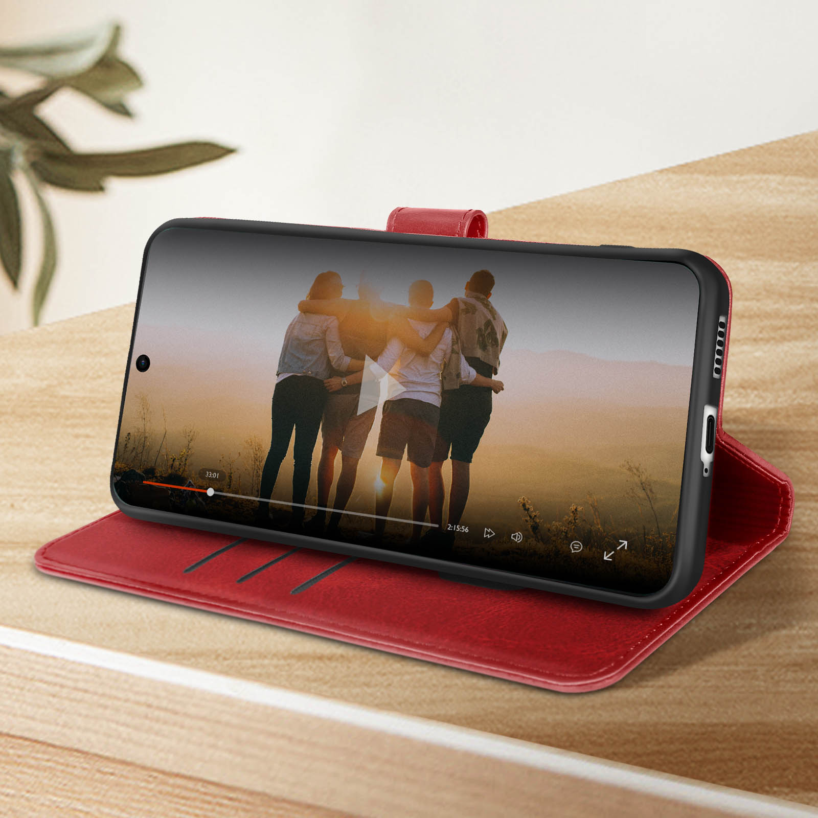 Telefono in custodia rossa che mostra video di persone che si abbracciano al tramonto.