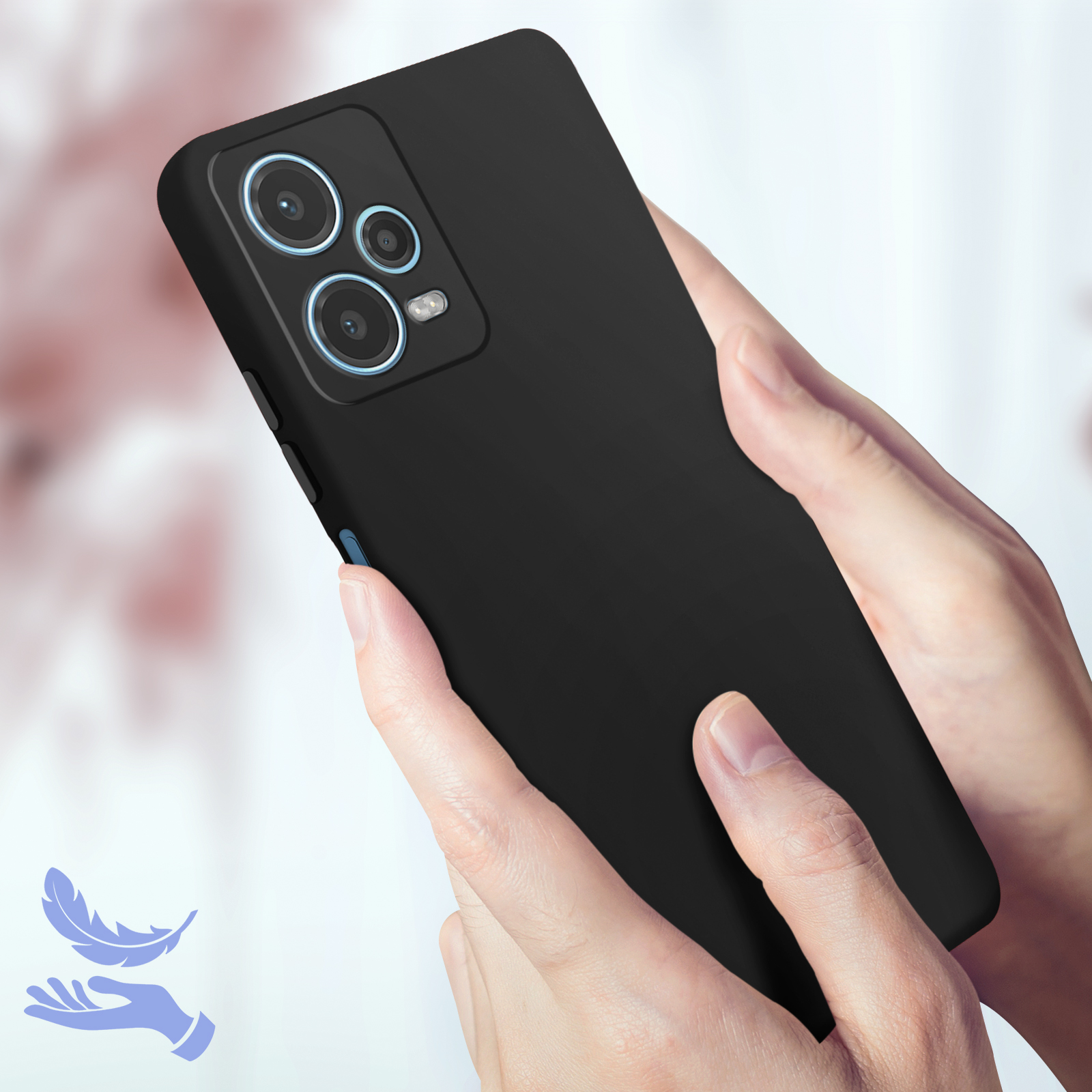 Una mano tiene un telefono nero. Il telefono ha tre fotocamere. Lo sfondo è sfocato. Icona piuma.