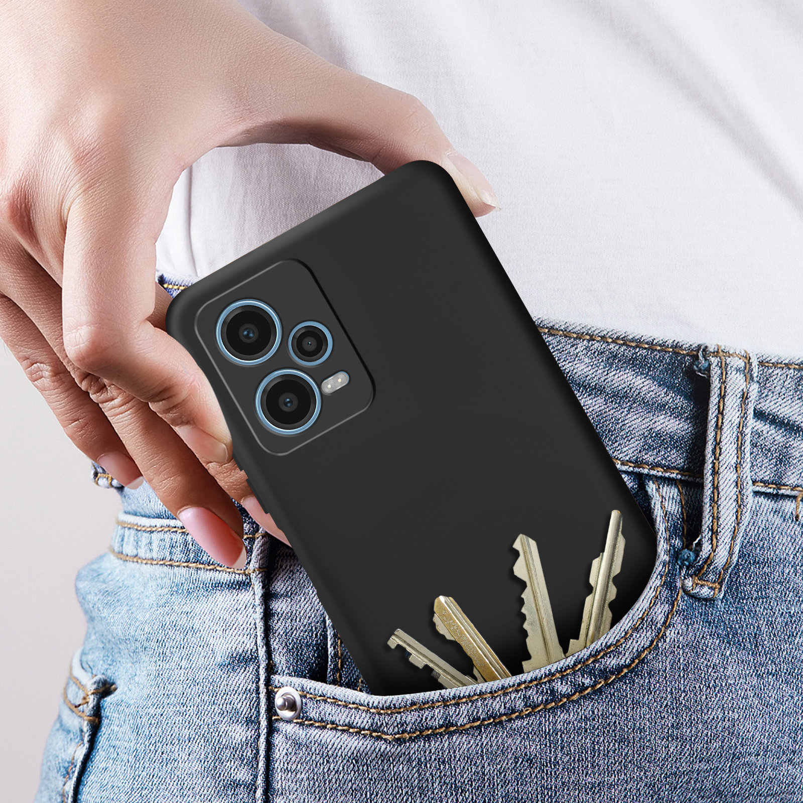 Una mano che mette un telefono nero in tasca con le chiavi.