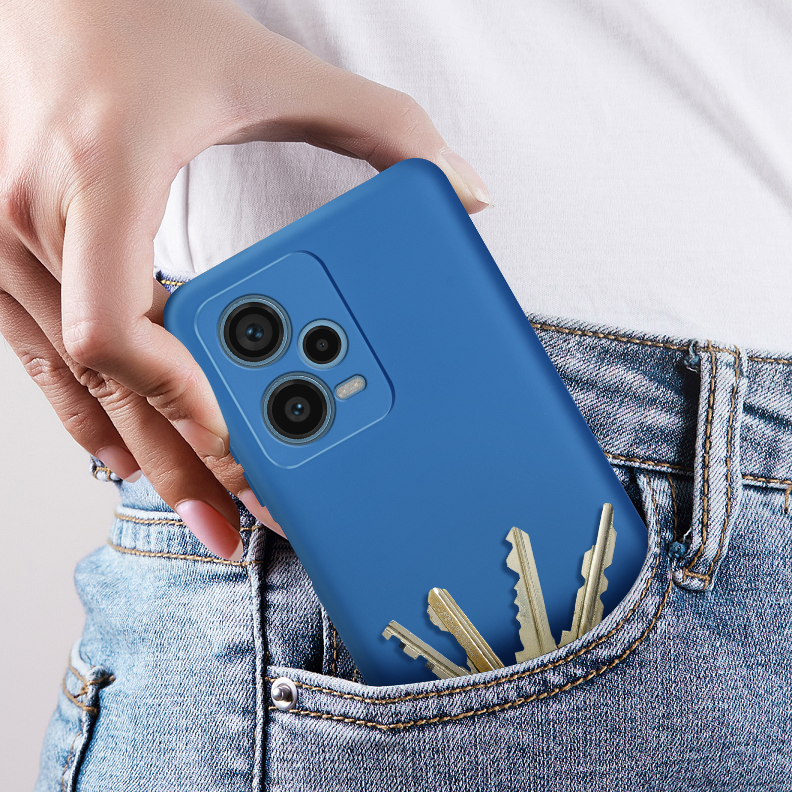 Mano in tasca di jeans con custodia blu e chiavi. La custodia è blu.