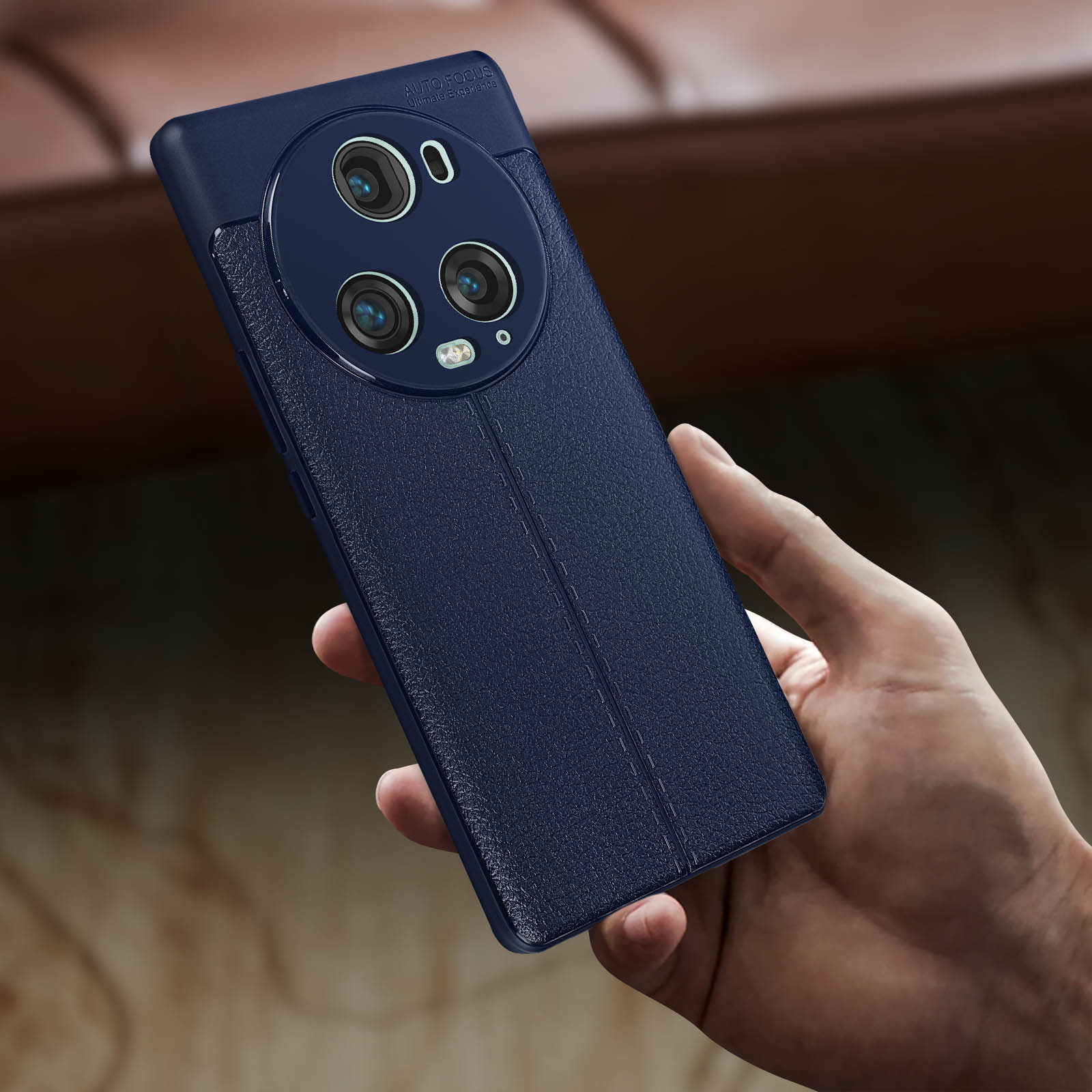 Una mano che tiene un telefono blu navy con tre fotocamere. Il retro è strutturato con cuciture.