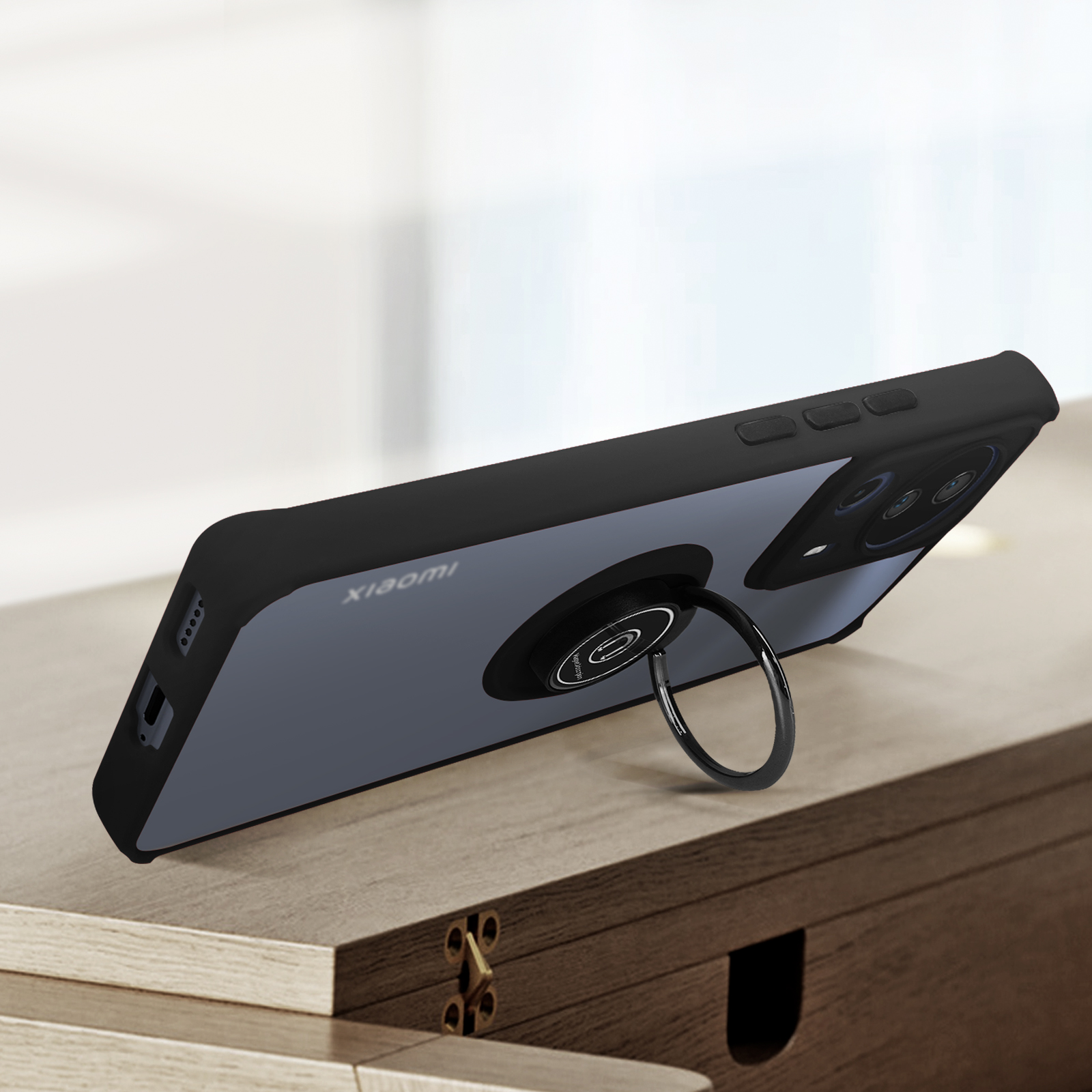 Custodia nera per telefono con supporto ad anello. Su superficie in legno, sfondo sfocato.