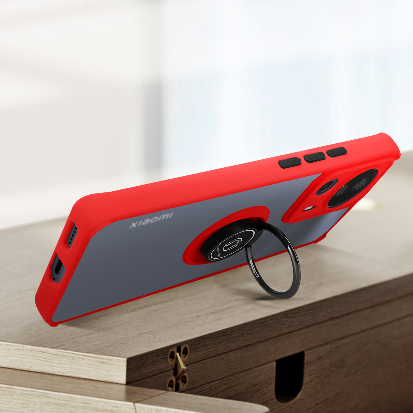 Custodia rossa, retro grigio. Anello nero. Logo Xiaomi. Su tavolo legno.