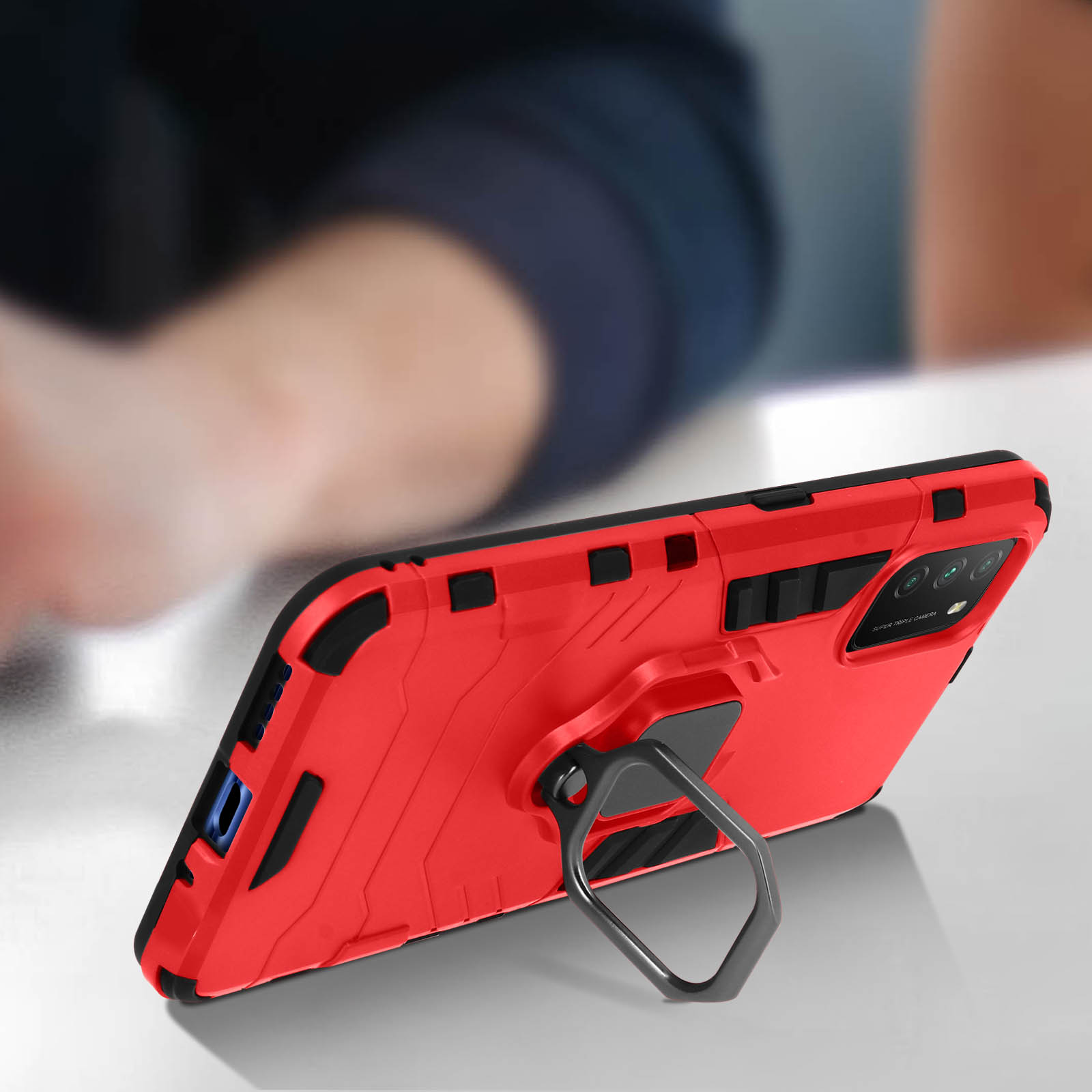 Rote Handyhülle mit Ringhalter, auf einem Tisch, schwarze Akzente.