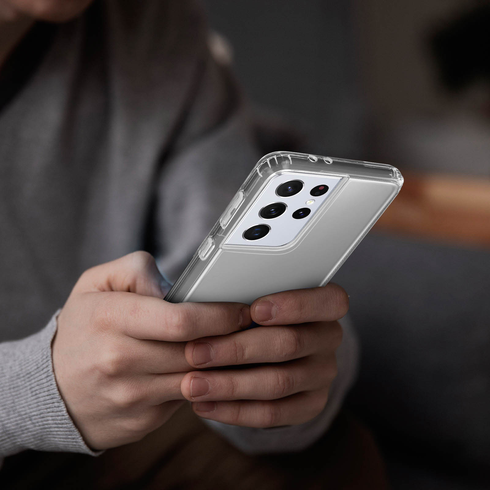 Mani che tengono un telefono con custodia trasparente. Il telefono è argento.