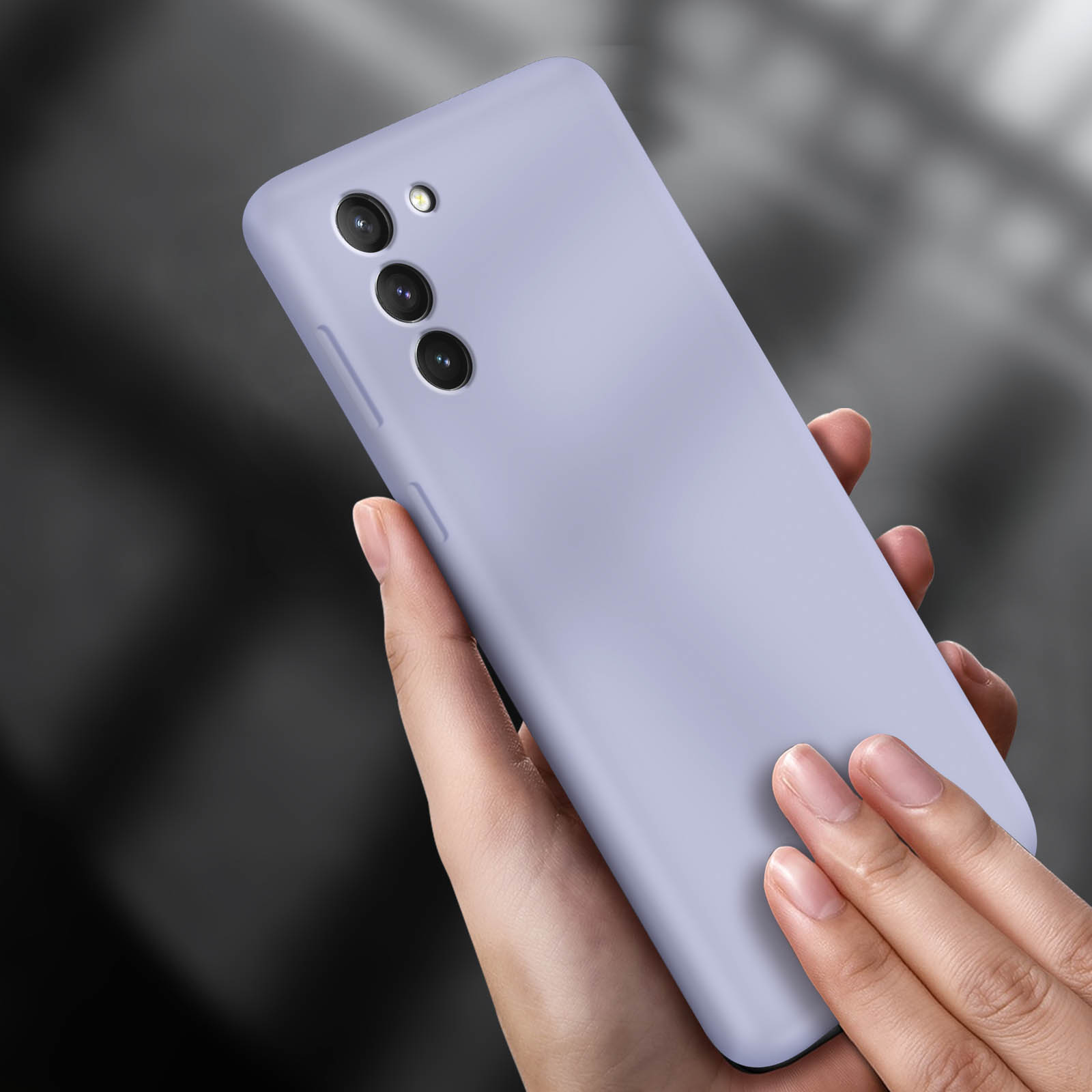 Una mano sosteniendo un teléfono lavanda, tres lentes de cámara visibles.