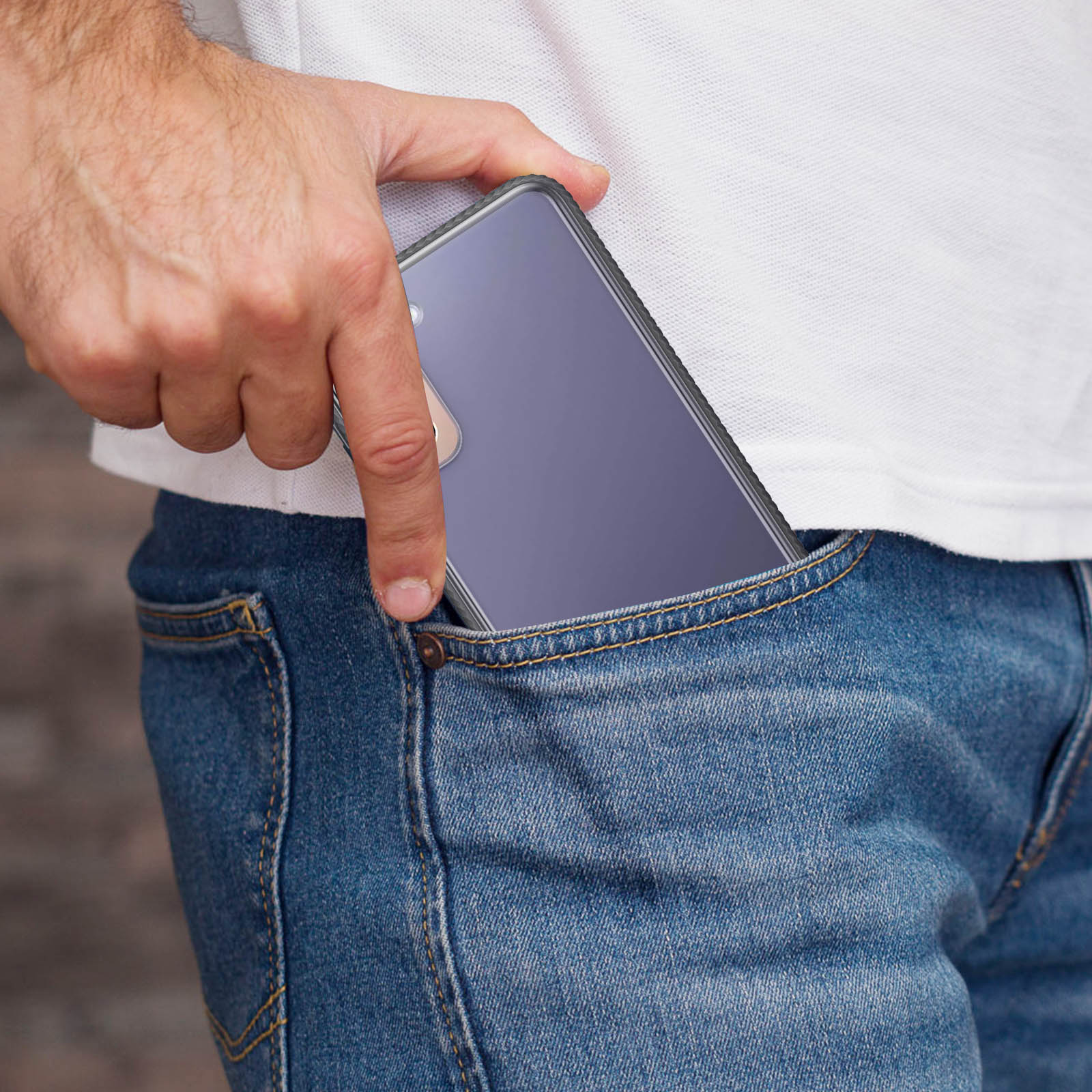Hand stopt telefoon in jeanszak. Telefoon heeft een doorzichtige hoes.