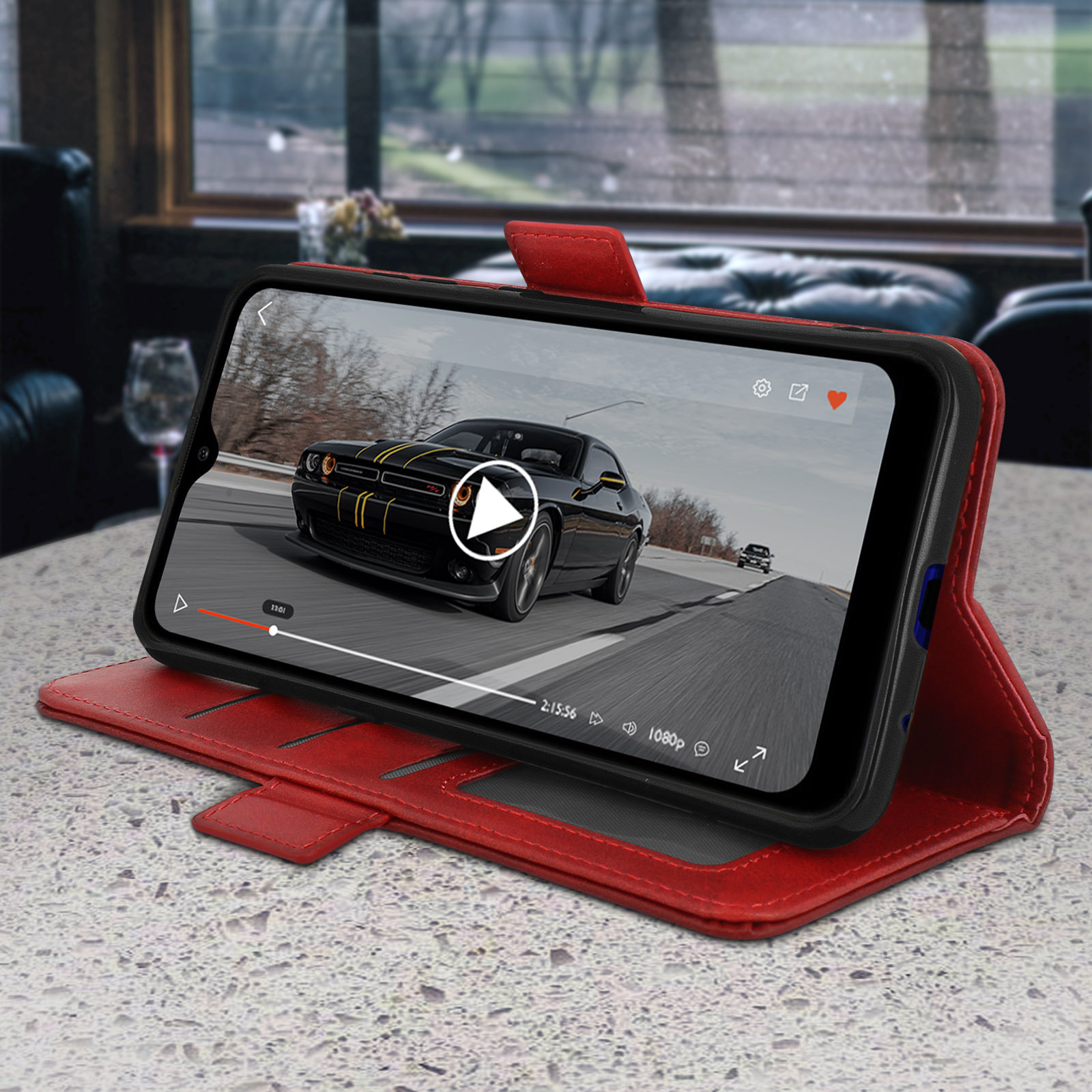 Rote Handyhülle mit einem Telefon, das ein Autovideo anzeigt. Die Szene ist drinnen.
