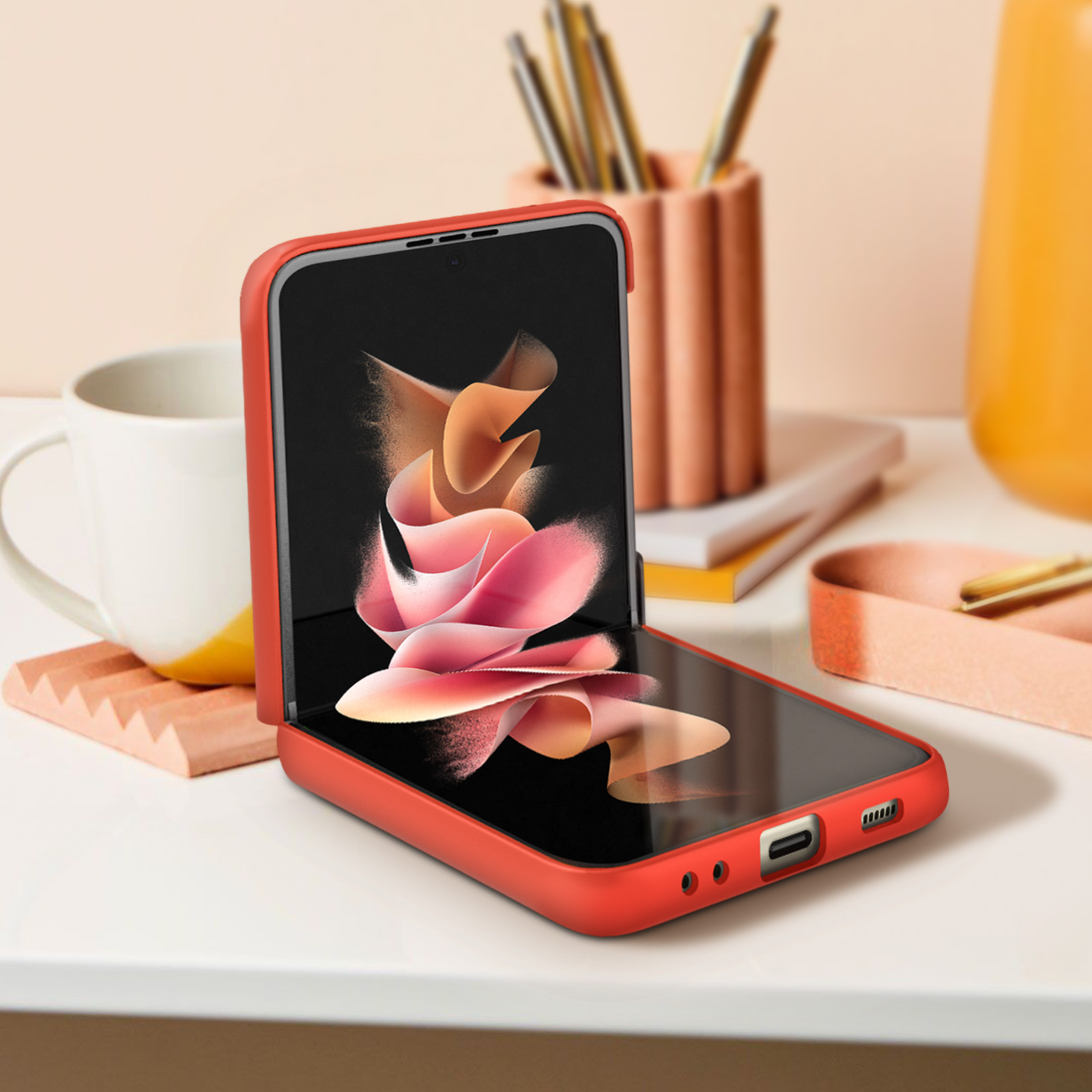 Rote Handyhülle mit Telefon darin, halb geöffnet, auf weißem Tisch. Objekte im Hintergrund.