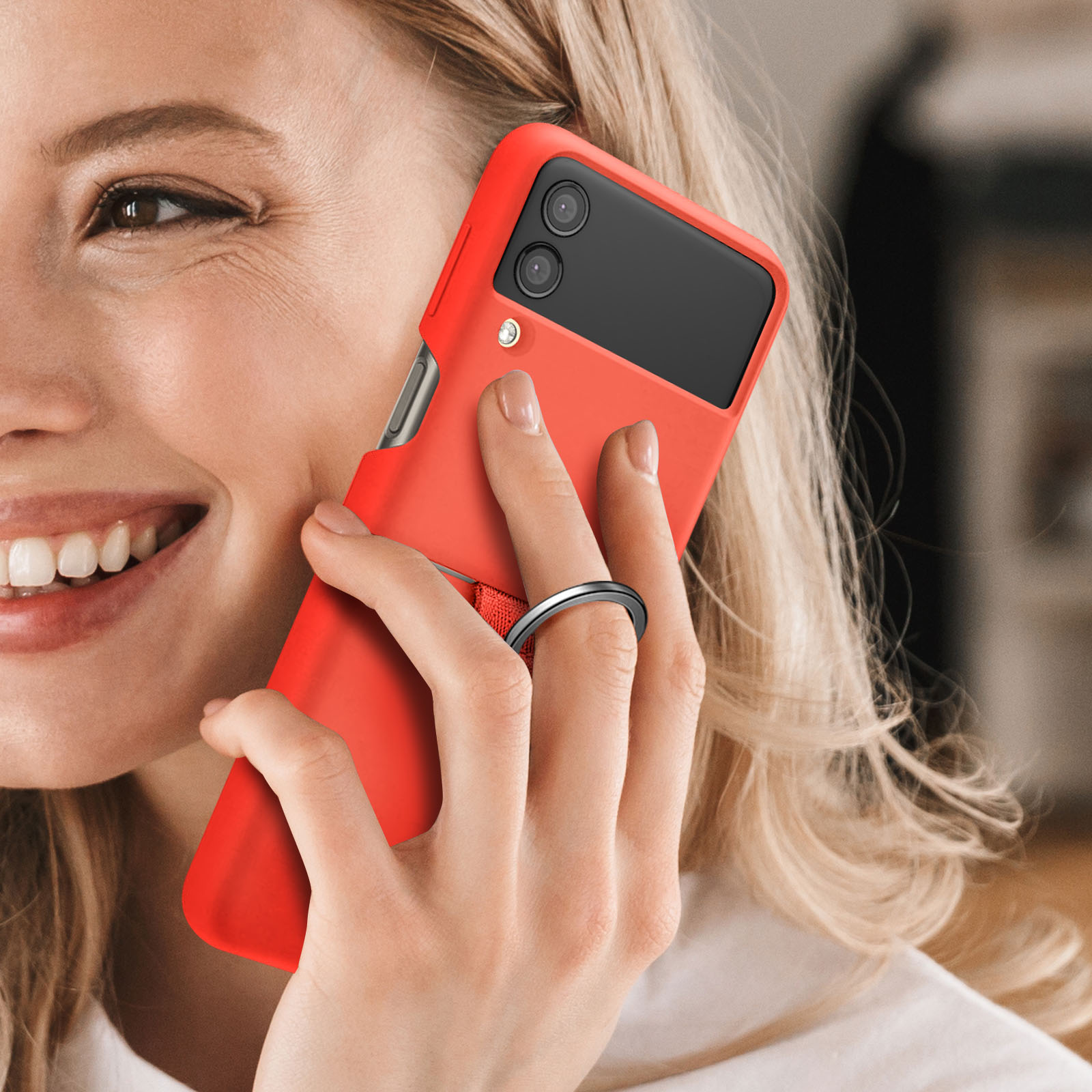 Frau hält rotes Telefon mit Ringhalter. Lächelt. Die Handyhülle hat einen Ring.
