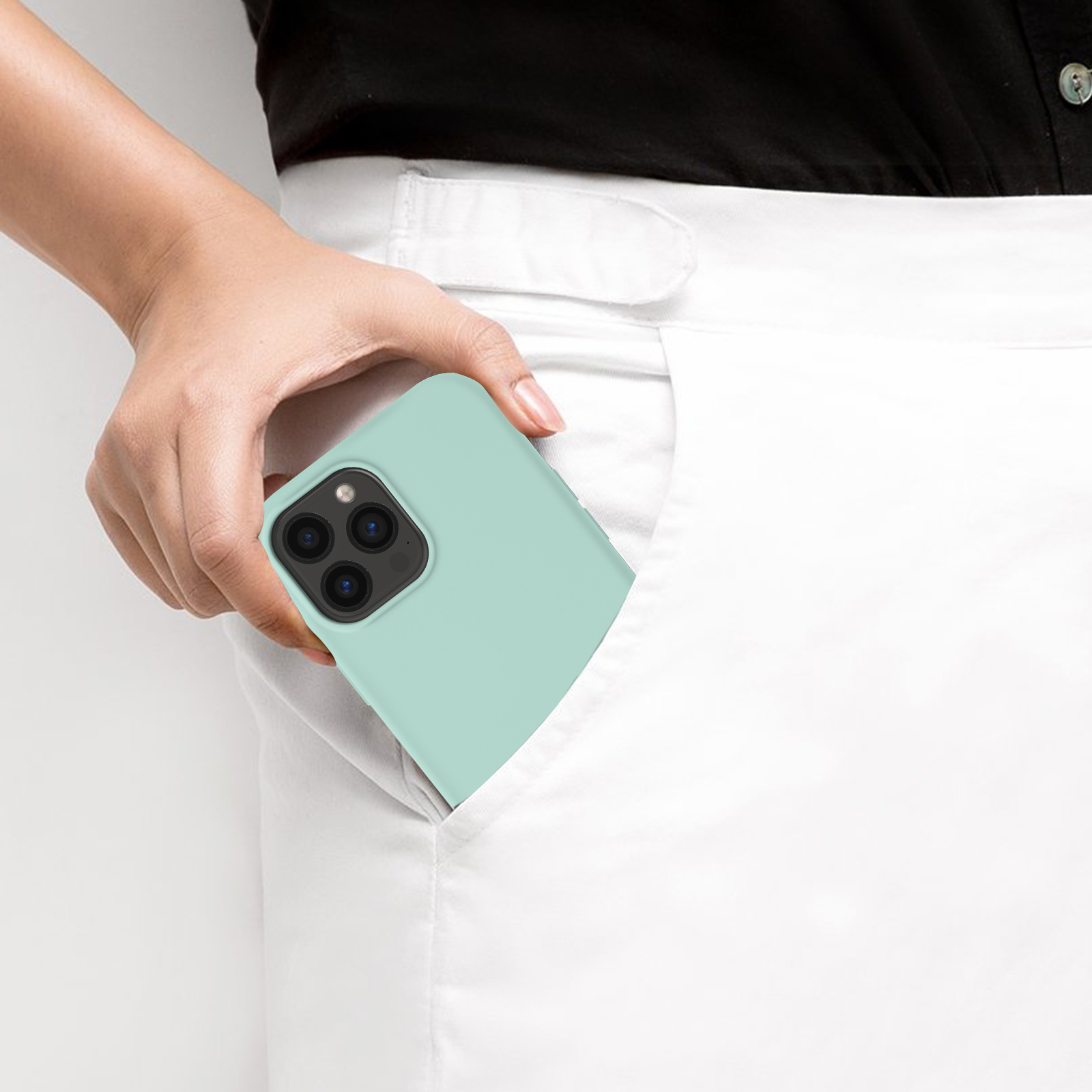 Hand steckt mintgrünes Telefon in weiße Hosentasche. Das Telefon hat Kameras.