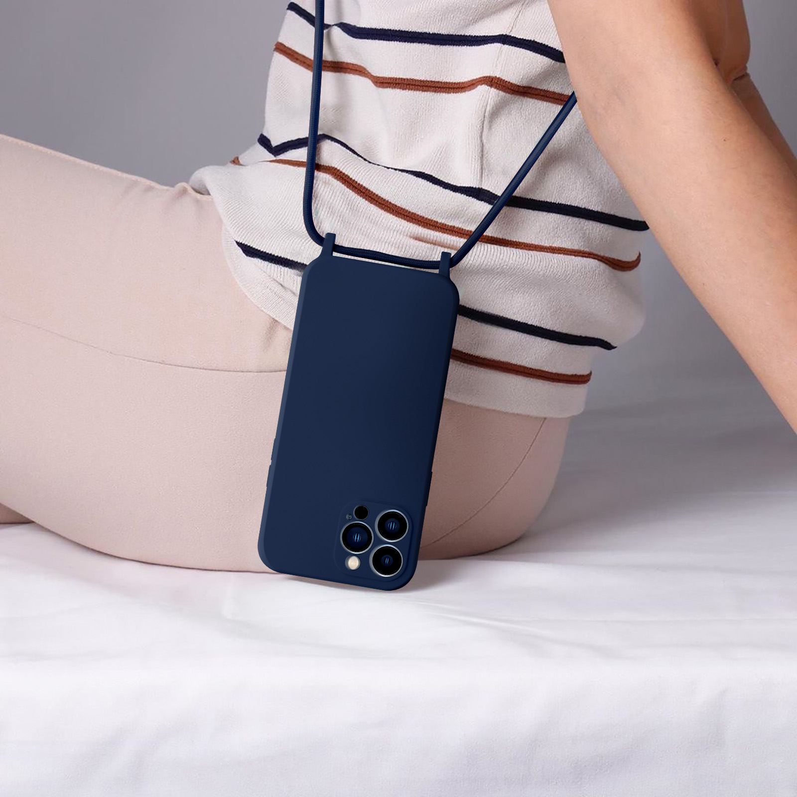 Un telefono blu navy con un cordino attaccato, appeso contro i vestiti beige di una persona.