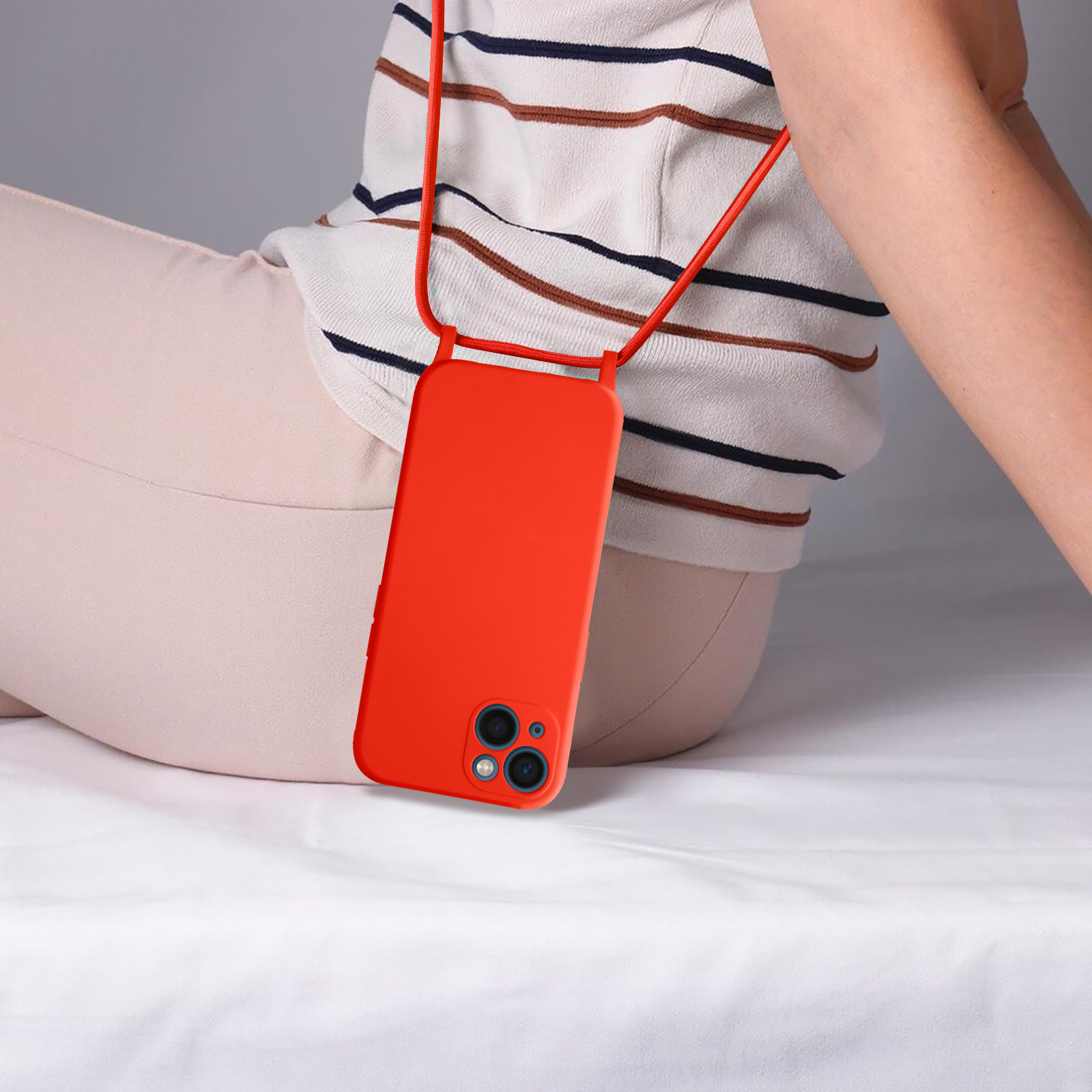 Een persoon draagt een oranje telefoonhoesje met een rode nekriem. De telefoon hangt voor het lichaam.