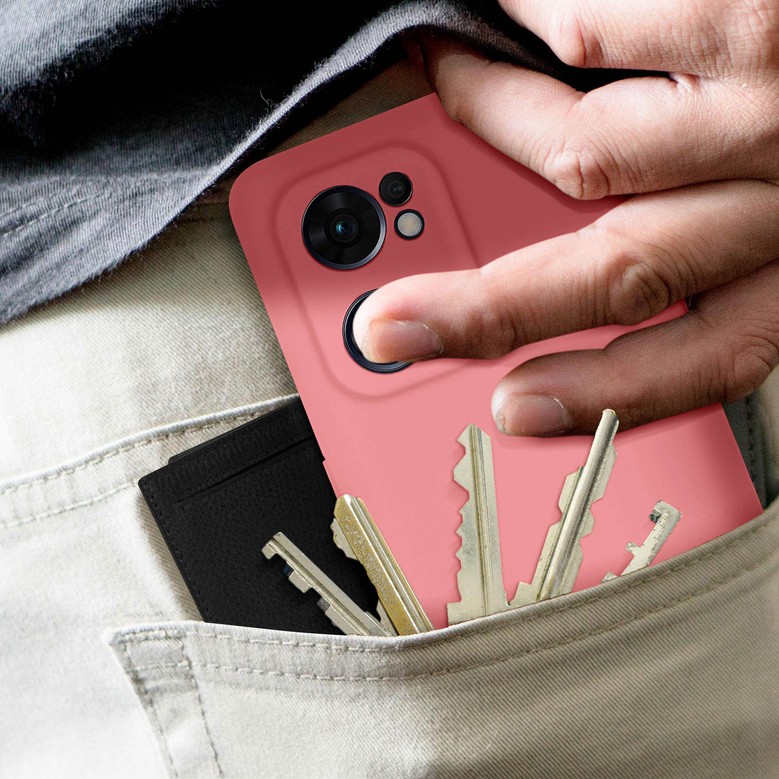 Mano che tiene un telefono rosa in tasca. Tre chiavi e una carta sono in tasca. Vengono indossati jeans.