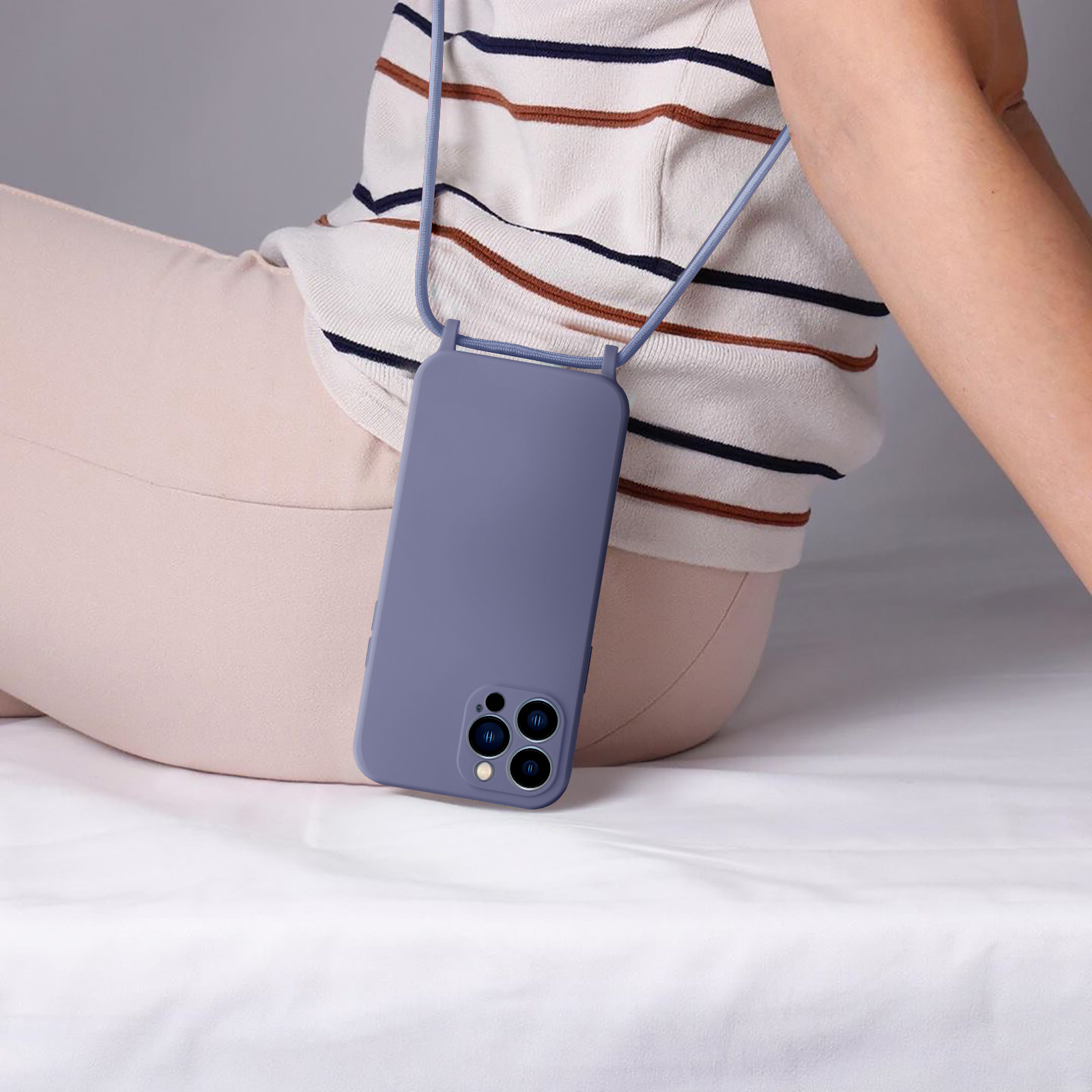 Une coque de téléphone avec une lanière est attachée à un téléphone. La personne est assise.