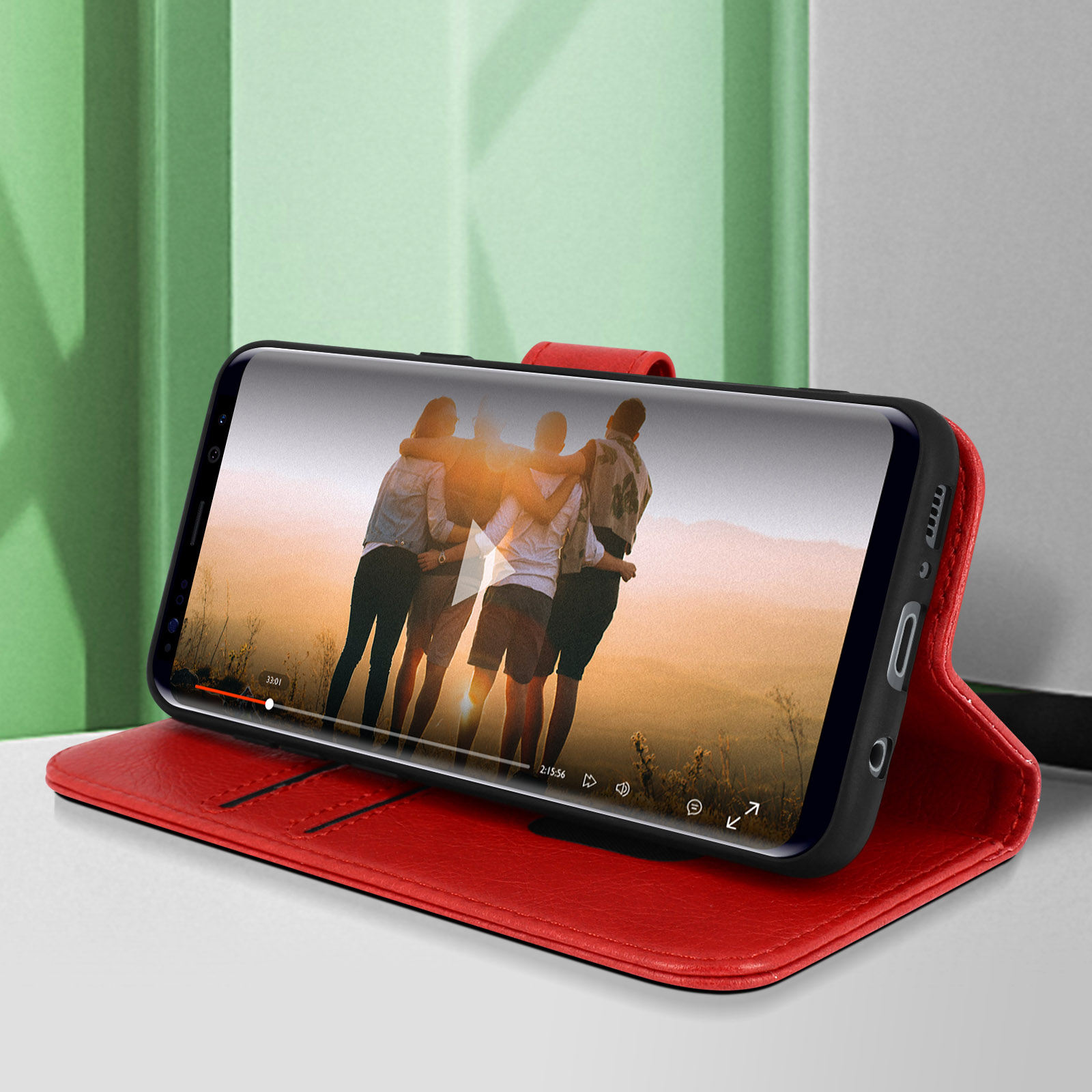 Téléphone dans un étui rouge lisant une vidéo d'une famille. L'étui est ouvert sur une table.