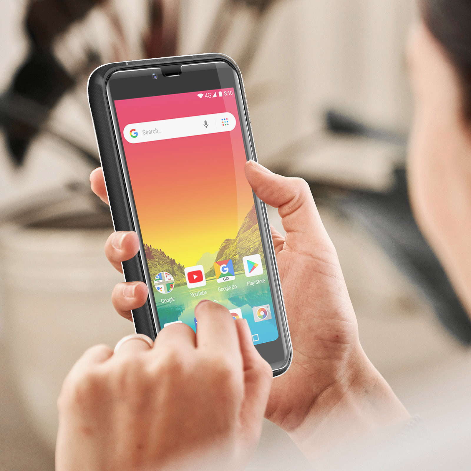 Eine Person hält ein Telefon mit einem Bildschirm, der eine Google-Suchleiste und App-Symbole zeigt. Der Hintergrund ist unscharf.