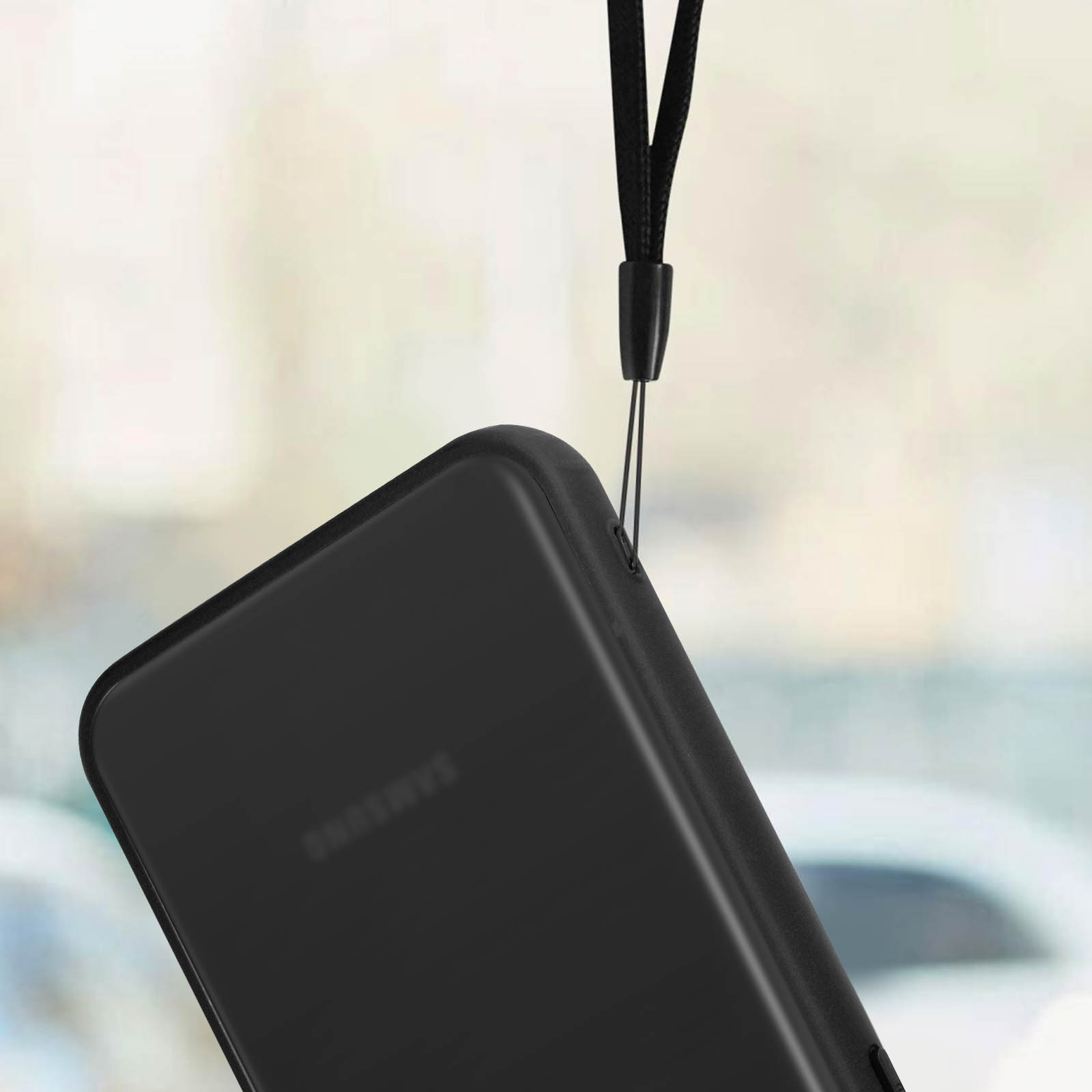 Zwarte telefoonhoes met een koord bevestigd, van bovenaf hangend. Het merk van de telefoon is Samsung.