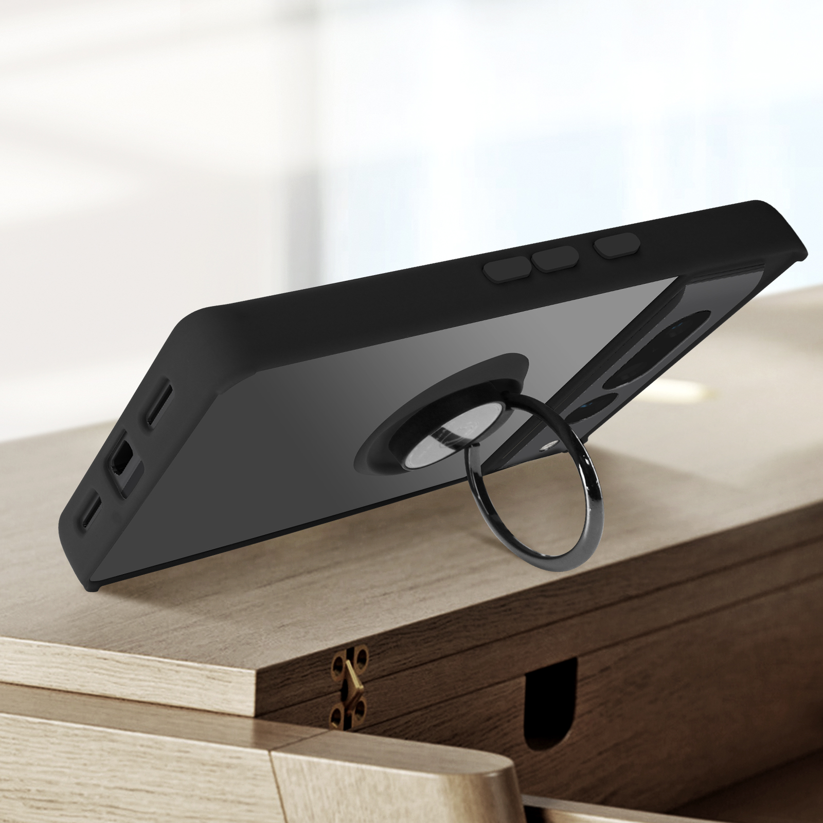 Een zwarte telefoon met een ringhouder op een houten oppervlak. De telefoon is zwart.