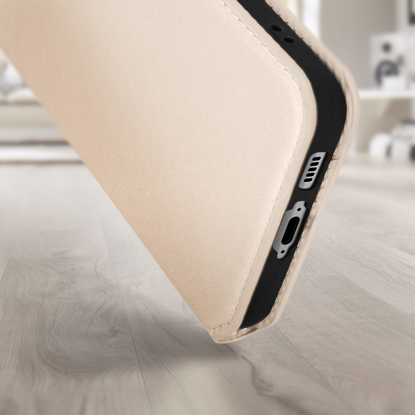 Una custodia per telefono color beige con bordi neri. È angolata su una superficie di legno. Sfondo sfocato.