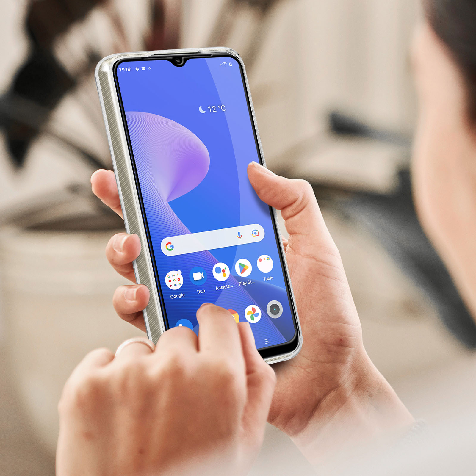 Una persona tiene in mano uno smartphone con una custodia trasparente. Lo schermo mostra un'interfaccia.