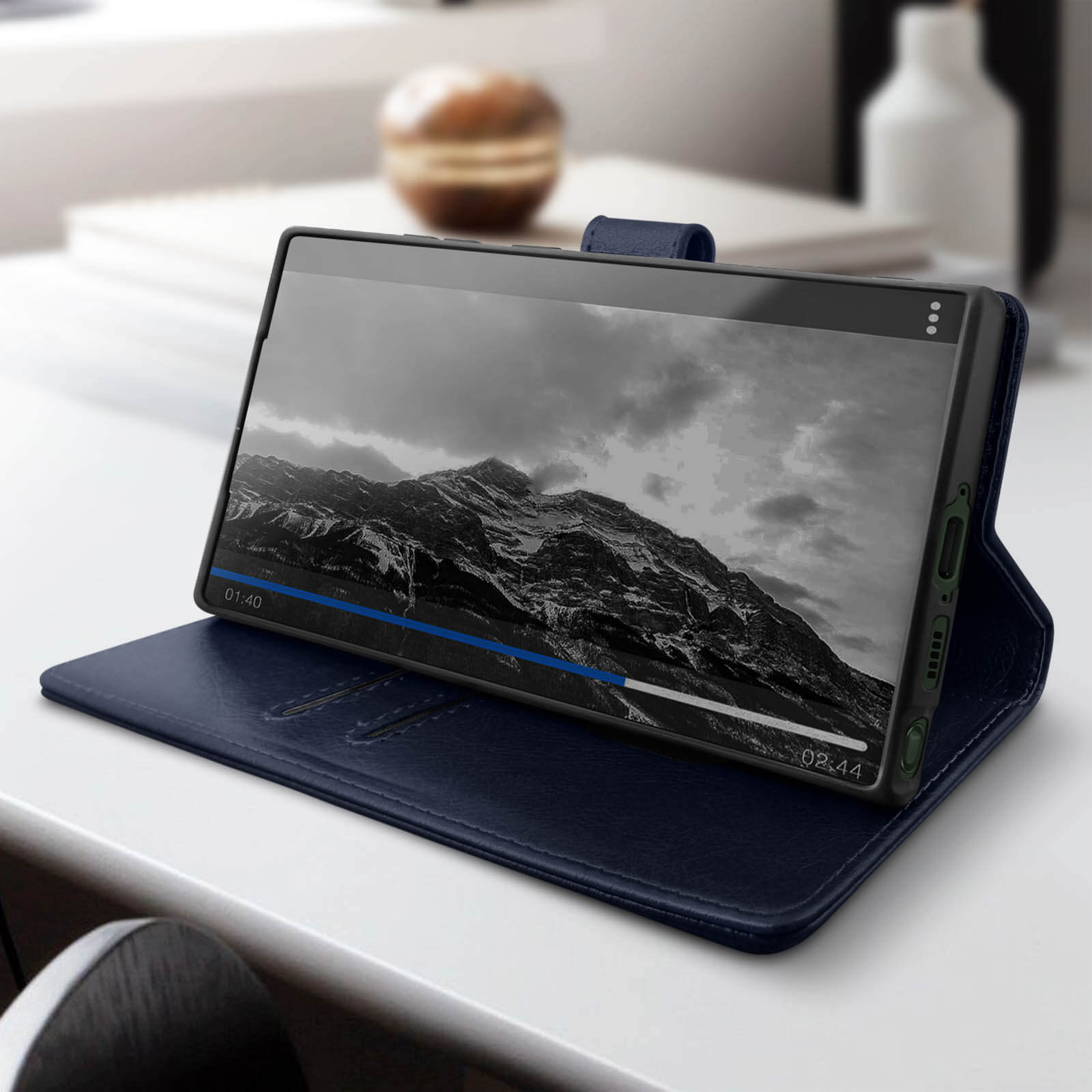 Una custodia per telefono blu scuro. È aperta, con un telefono all'interno che riproduce un video. Lo sfondo è sfocato.
