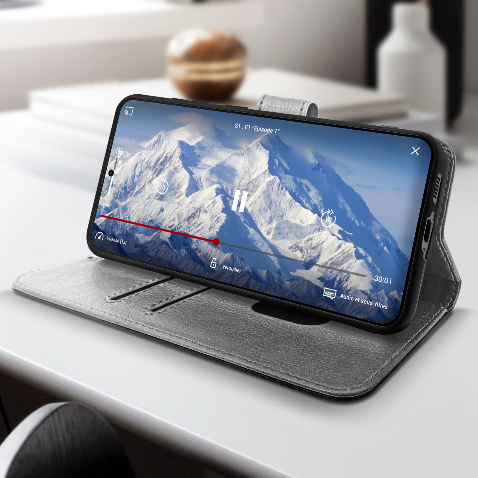 Ein Telefon, das ein Video abspielt. Das Telefon befindet sich in einem grauen Case auf einem weißen Tisch.