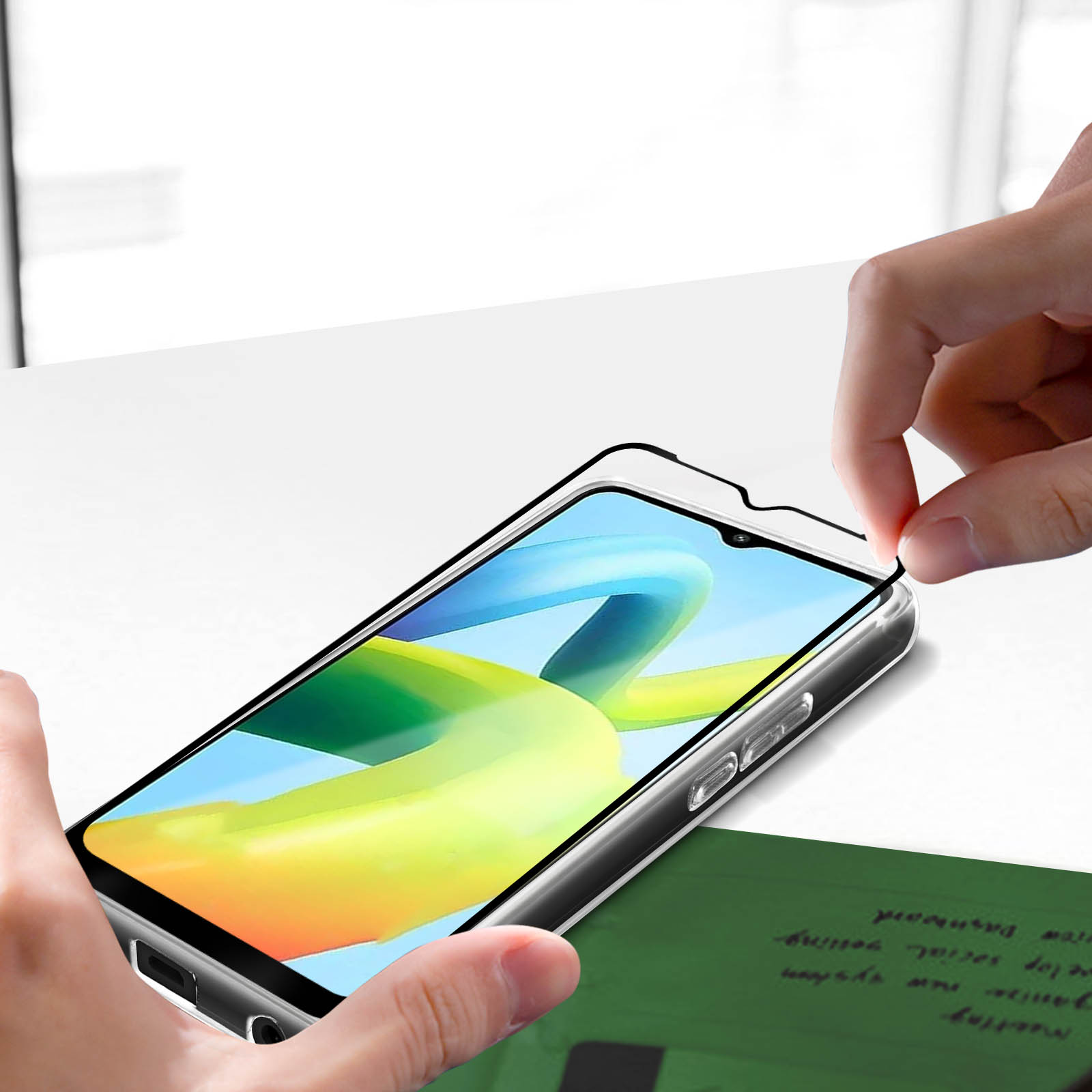 Mani che applicano una protezione per lo schermo su un telefono. Il telefono è su una superficie bianca.