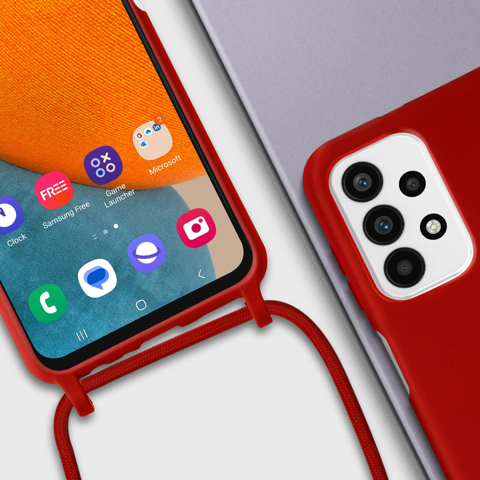 Telefoon met rode hoes, apps op scherm. Rood koord bevestigd. Andere telefoon met grijze hoes rechts.