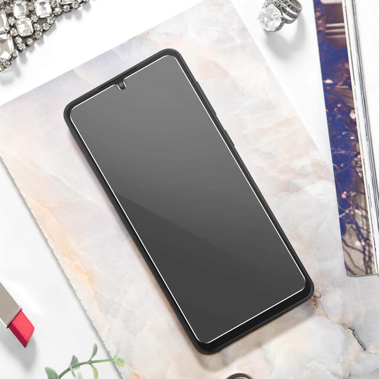 Zwart telefoonscherm, liggend op marmeren oppervlak. Sieraden en lippenstift aan de zijkant.