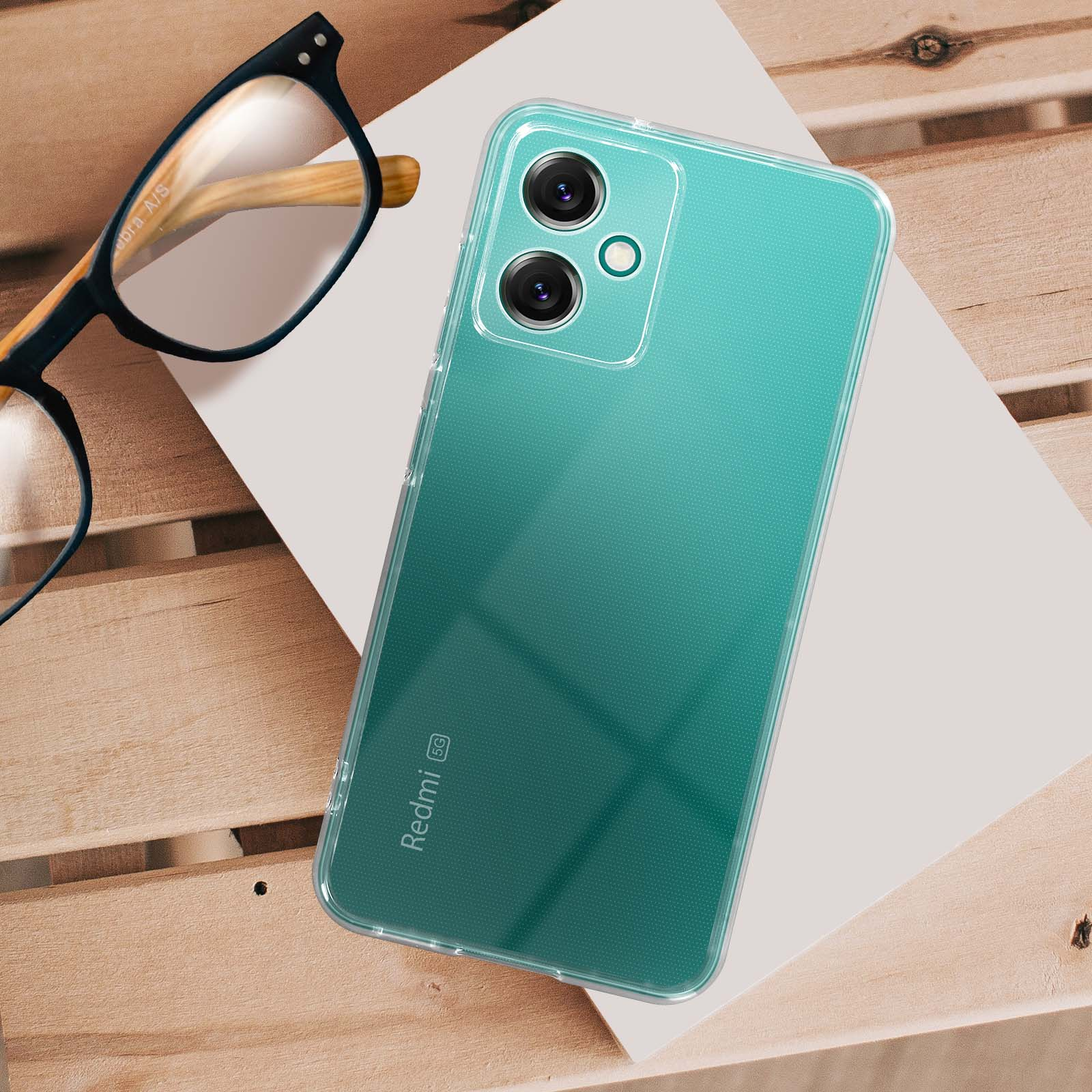 Una custodia trasparente per telefono su una superficie di legno con occhiali e carta bianca. Logo Redmi 5G.