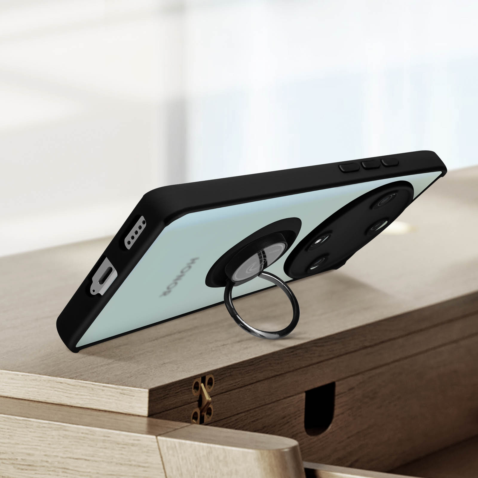 Un telefono nero con un supporto ad anello appoggiato su una superficie di legno. Una custodia nera per telefono.
