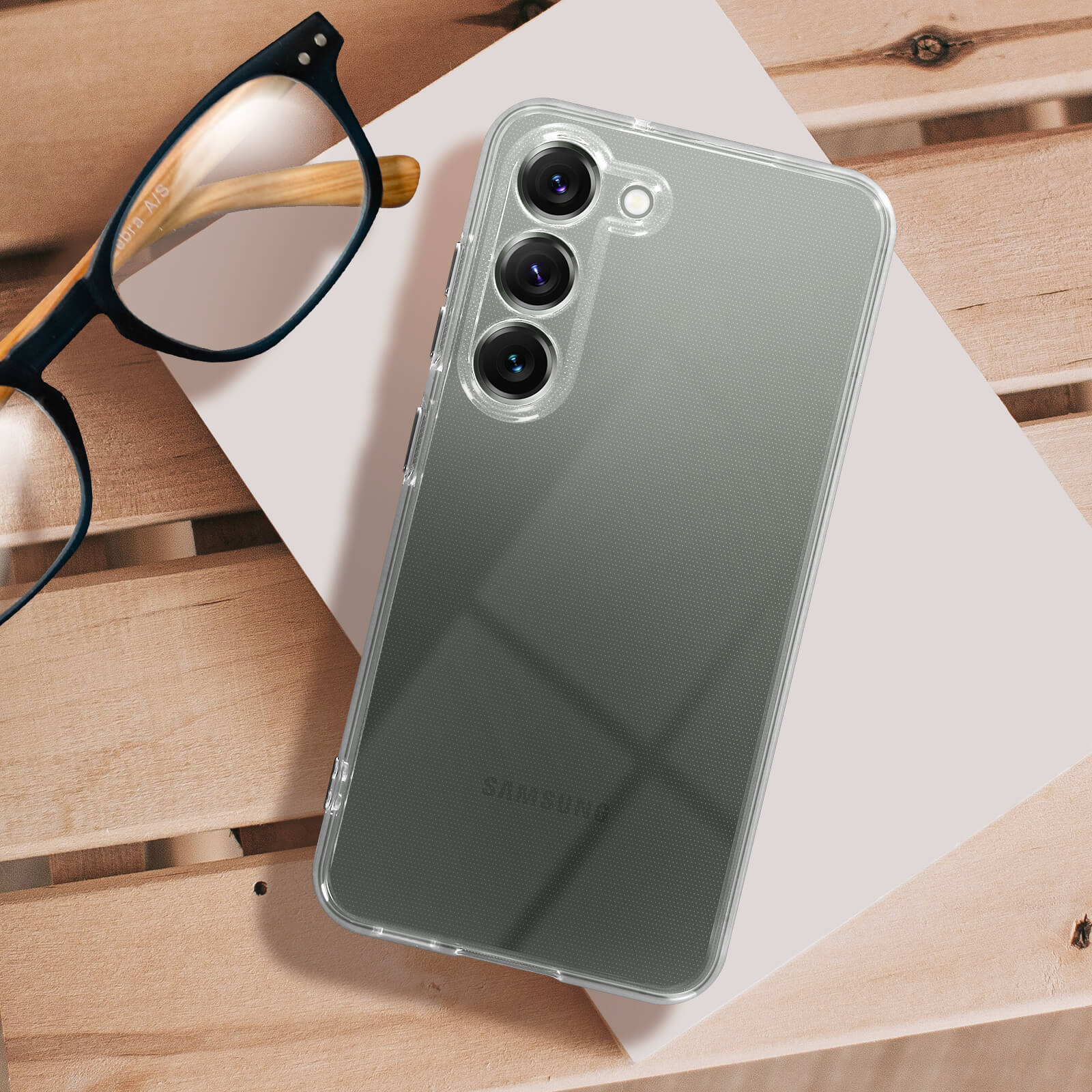 Transparante telefoonhoes met telefoon erin, bril op houten tafel.
