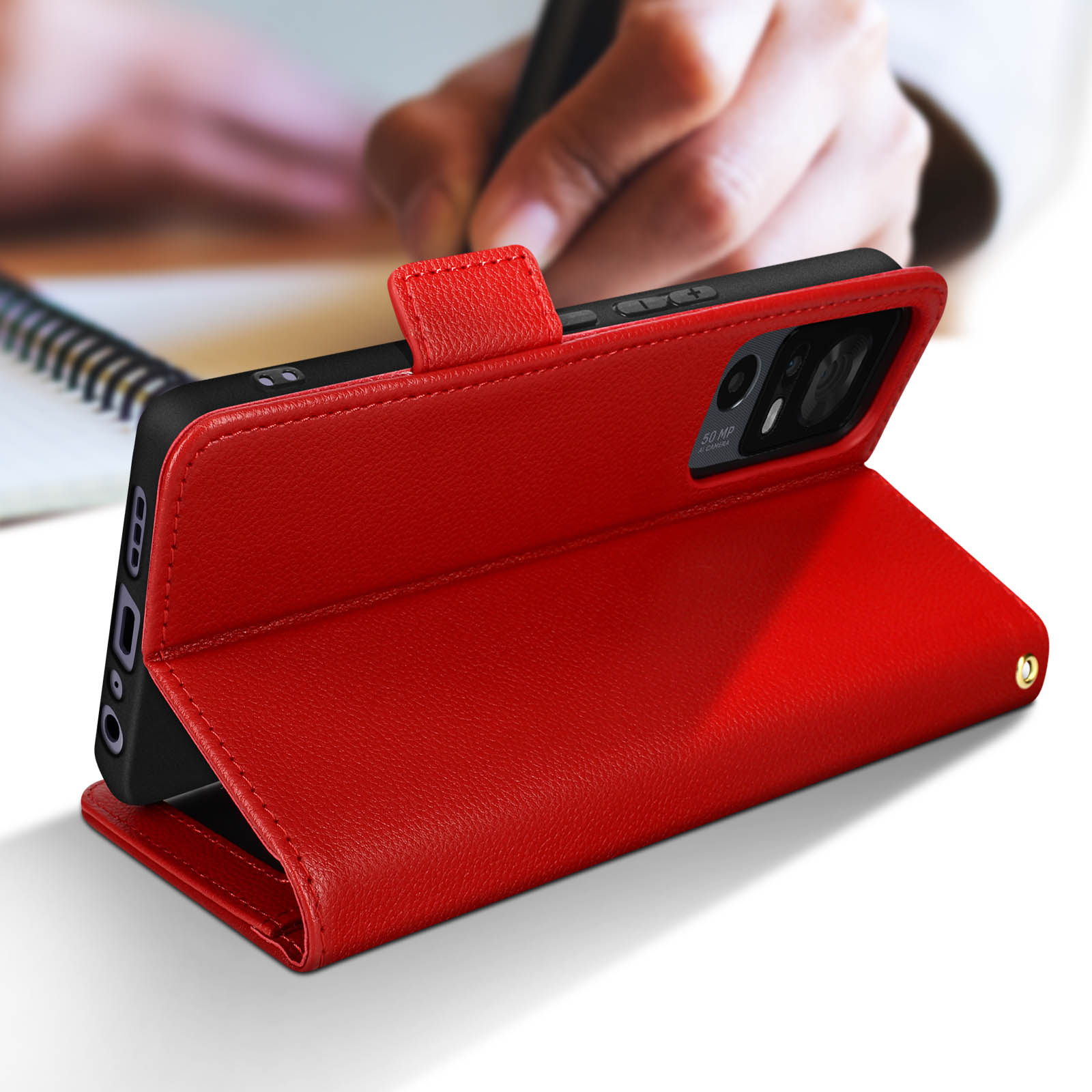 Una custodia in pelle rossa, aperta per rivelare un telefono nero. Una mano sta scrivendo sullo sfondo.