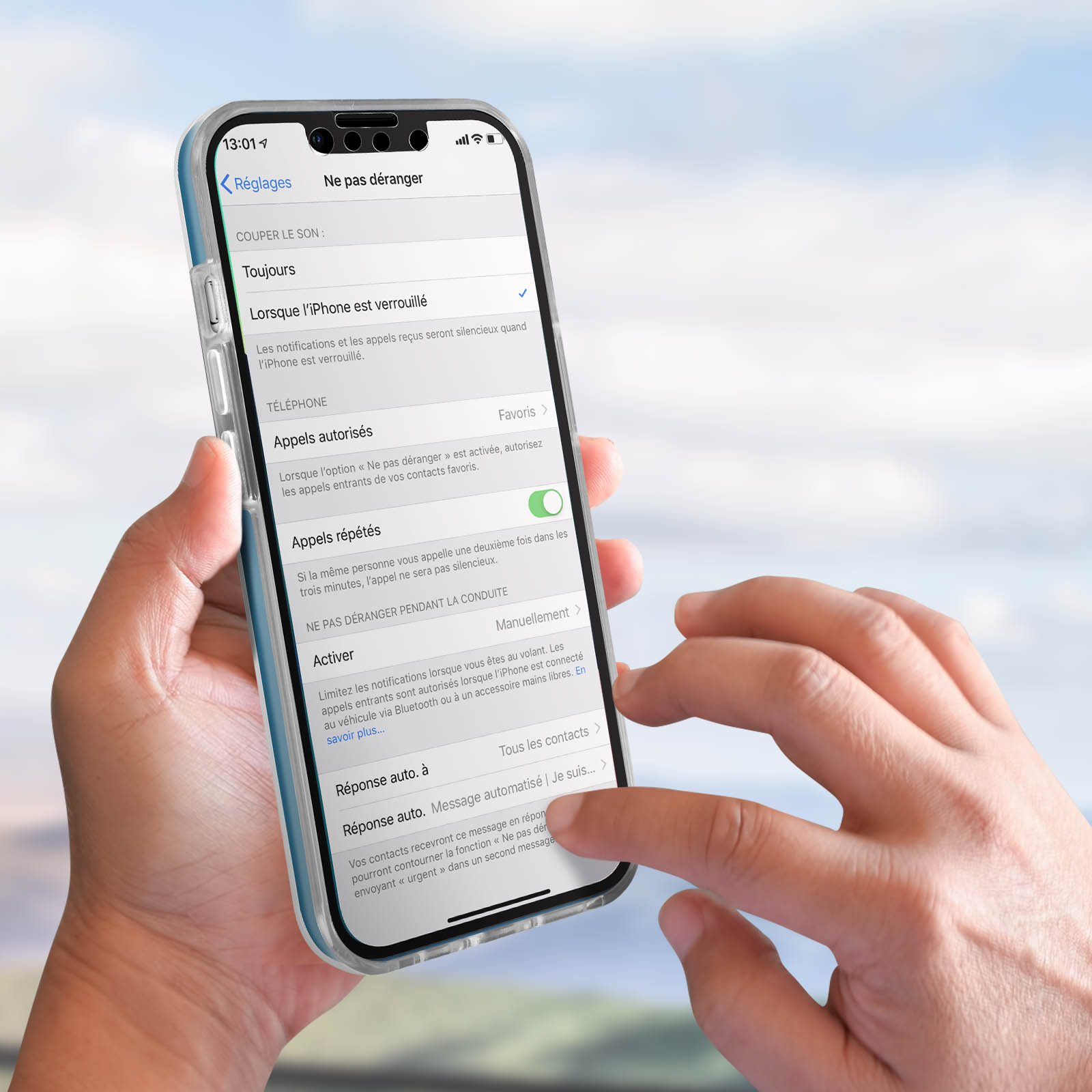 Una mano tiene un iPhone con il menu delle impostazioni aperto in francese. Lo sfondo è sfocato.
