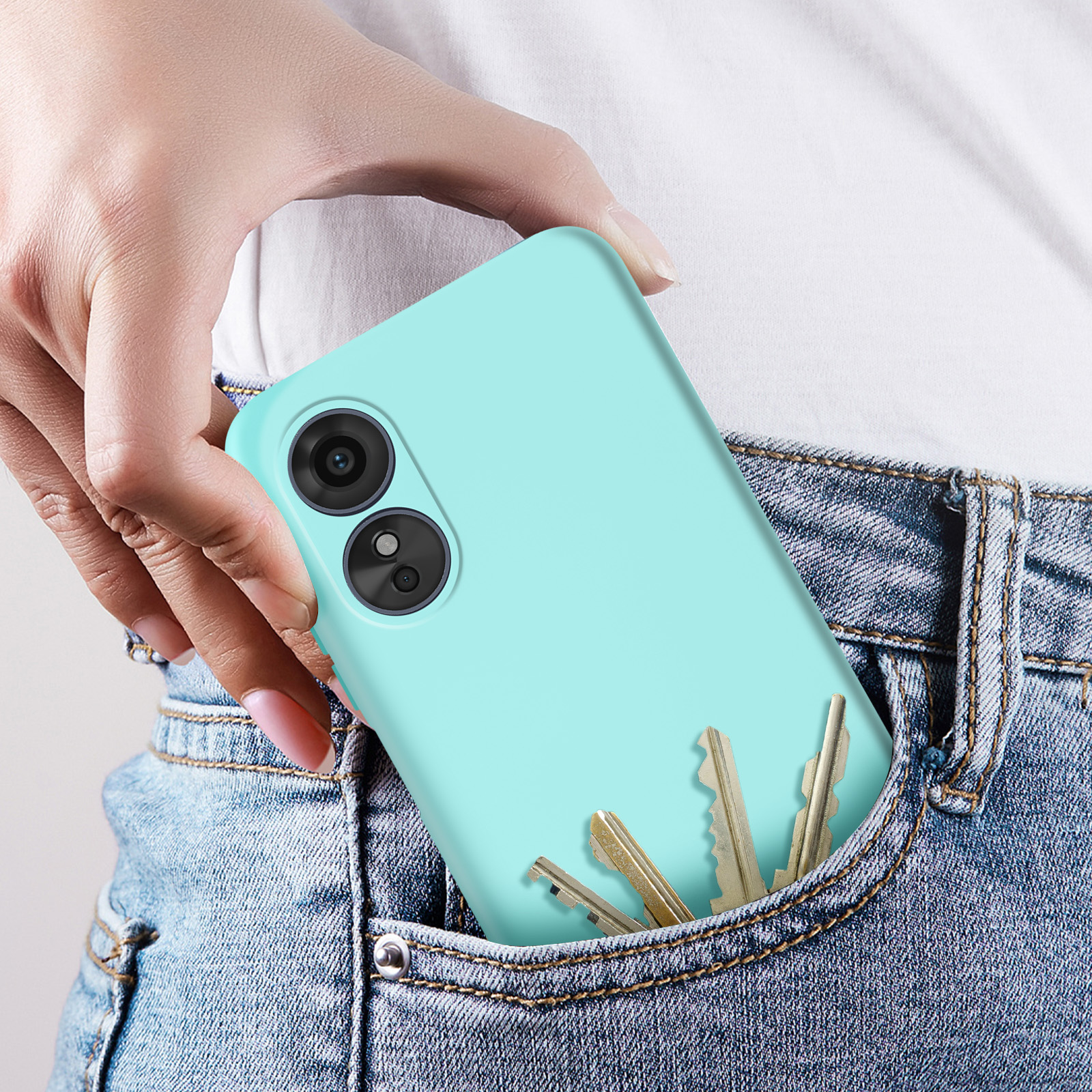 Una mano che tiene un telefono verde menta in una tasca dei jeans. Le chiavi sono nella tasca.