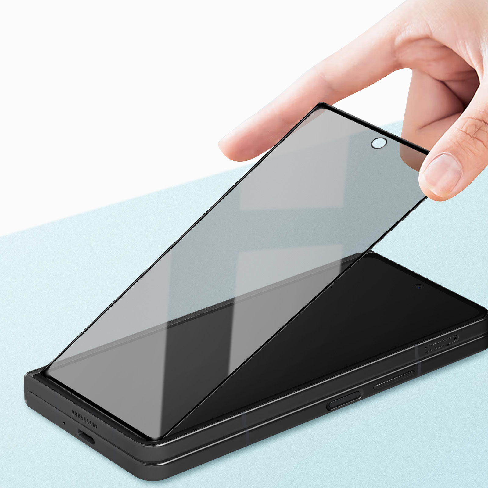 Hand legt Displayschutz auf ein schwarzes Telefon. Hellblauer Hintergrund.