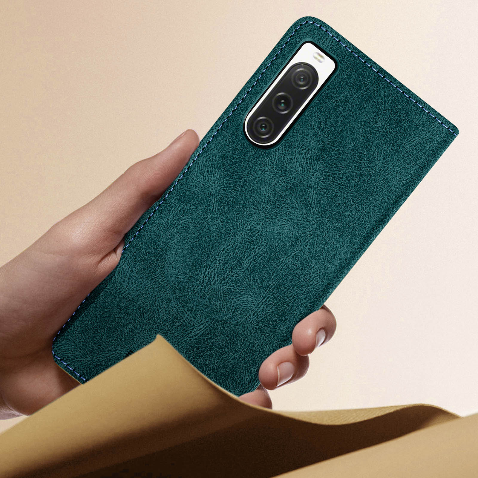 Mano che tiene una custodia per telefono verde acqua con un telefono. Sfondo marrone.
