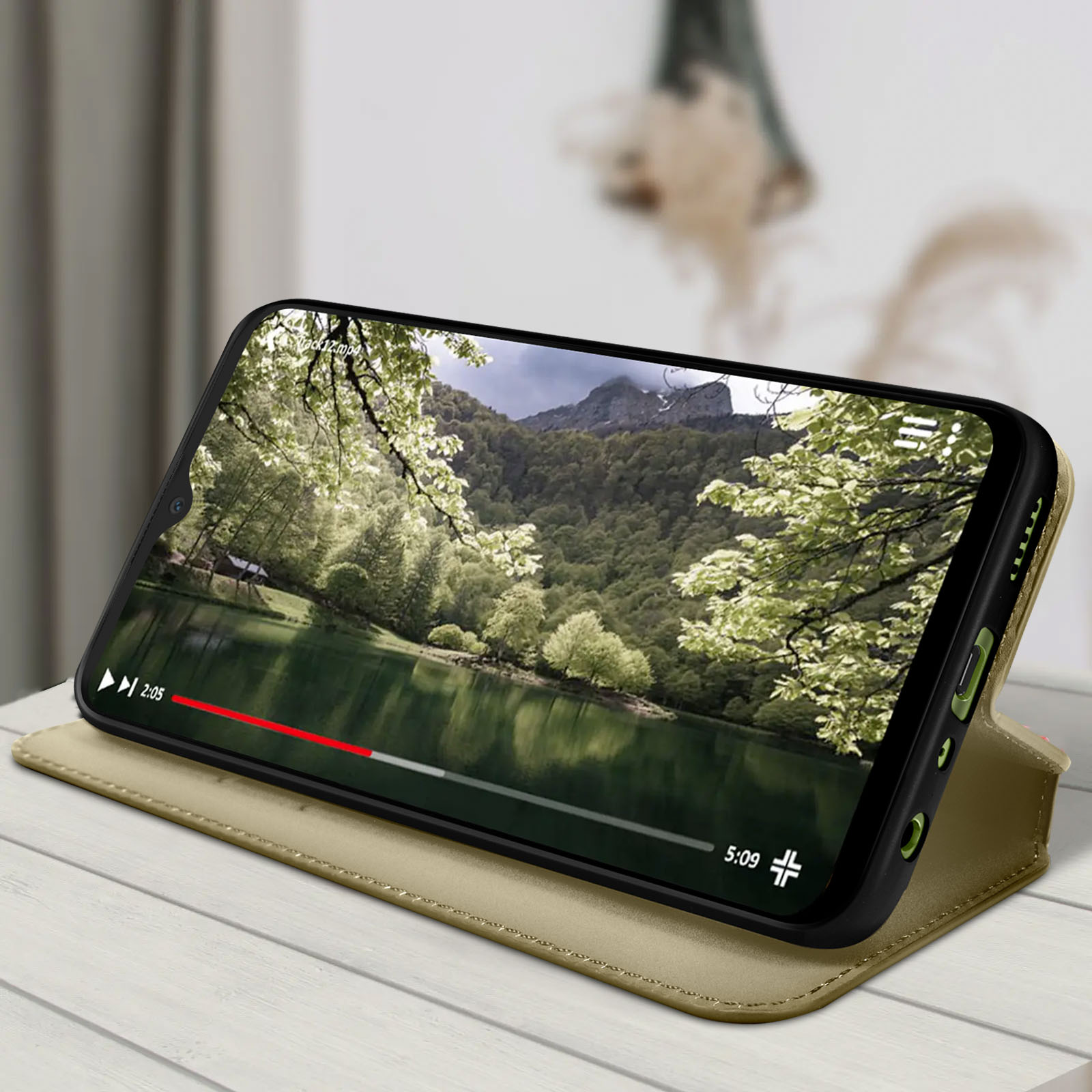 Smartphone in een bruine hoes met een video van een meer en bomen. Houten tafel.