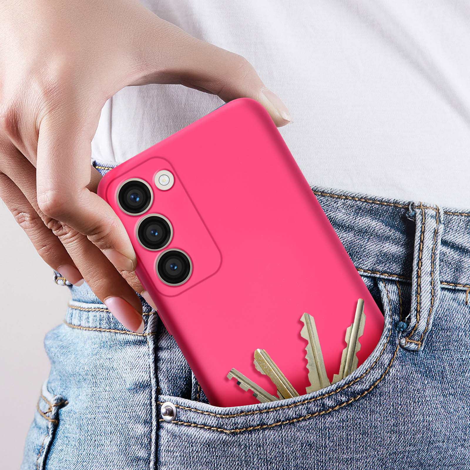 Mano che tiene un telefono rosa con chiavi in tasca. Il telefono è in una custodia rosa.