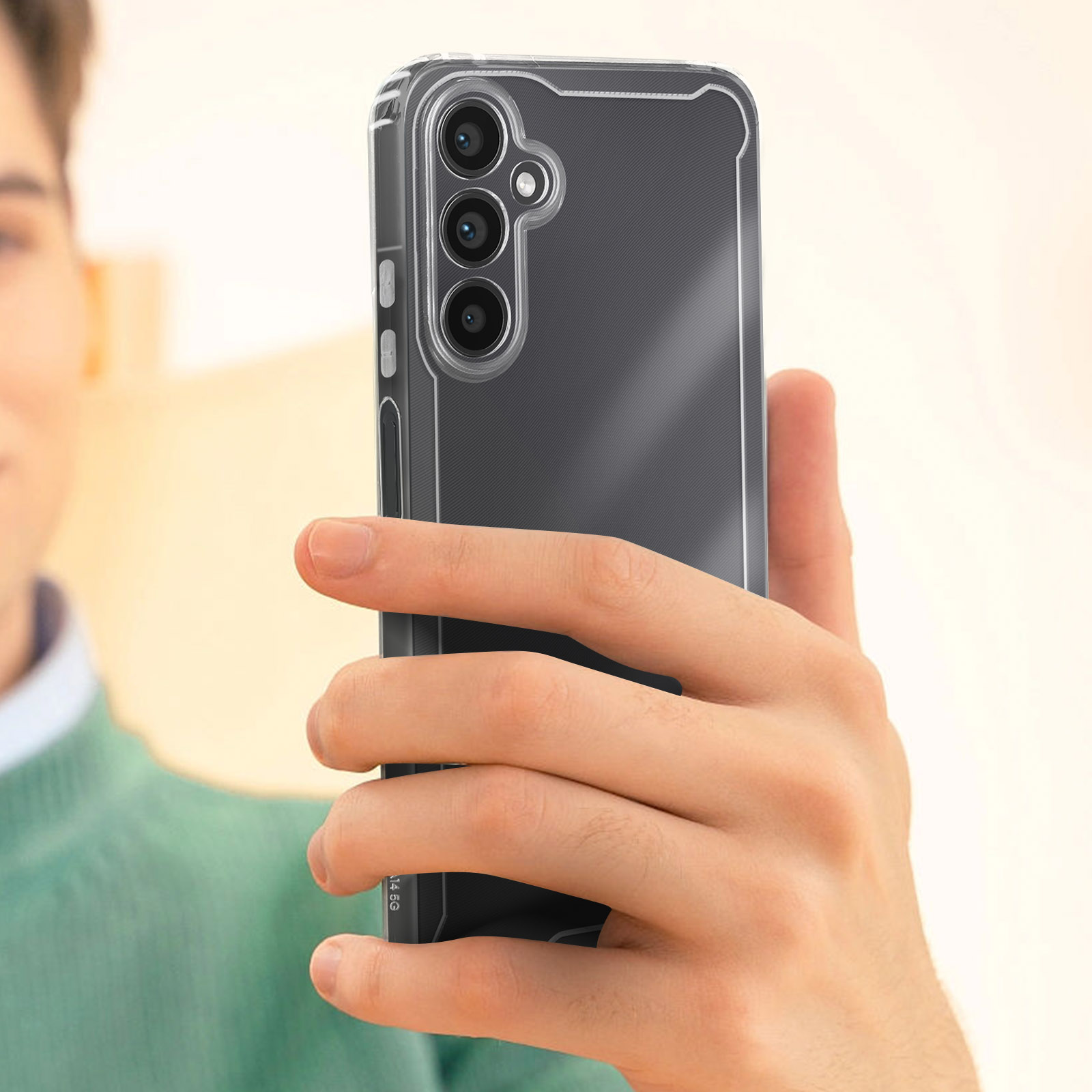 Une personne tenant un téléphone dans un étui transparent. Le téléphone a trois caméras et un cadre noir.