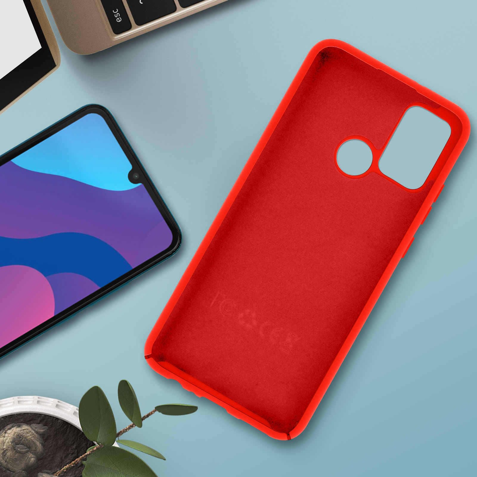 Una custodia rossa su una superficie blu con un telefono e alcune foglie.