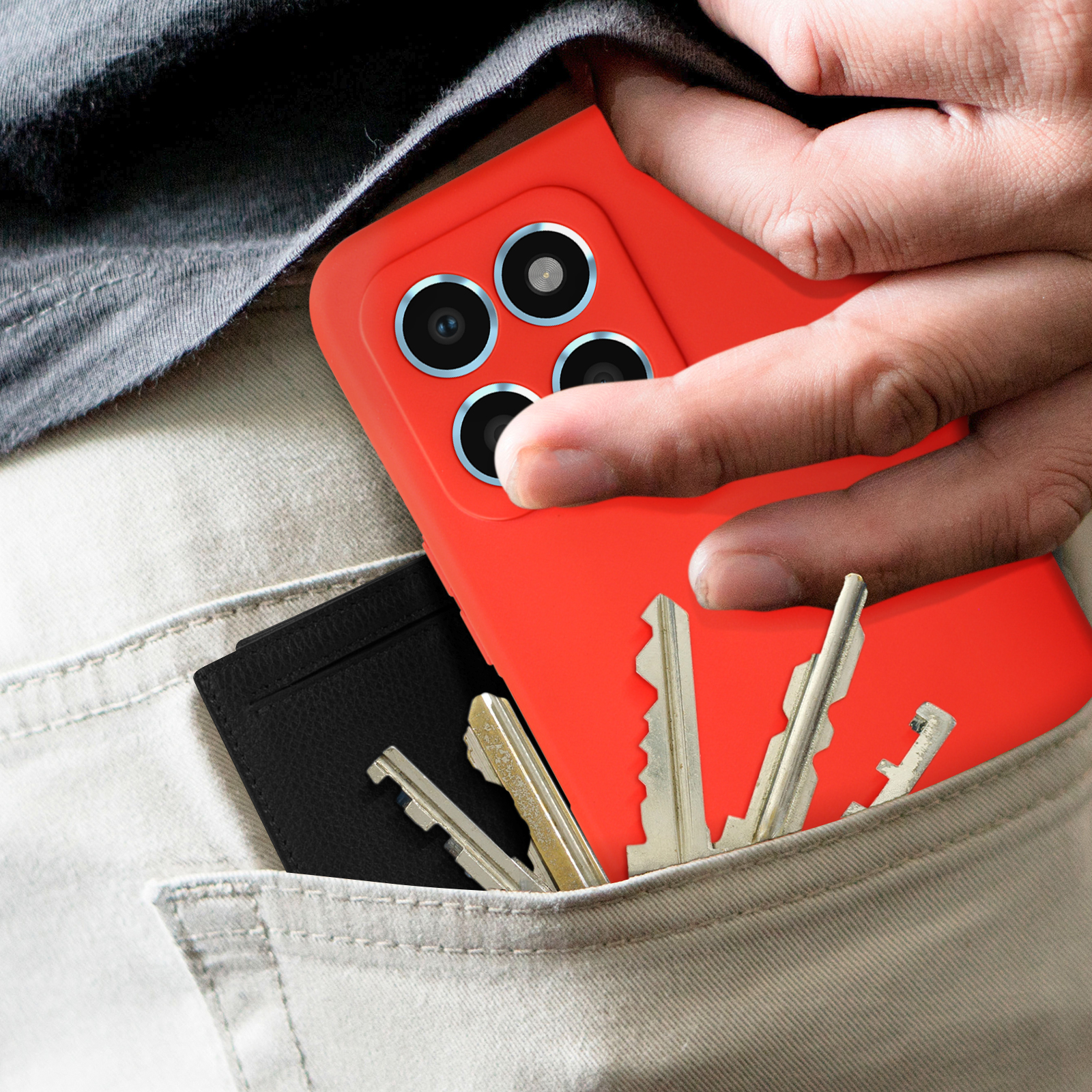 Main dans la poche avec clés et portefeuille noir. Téléphone avec coque orange dans la poche.