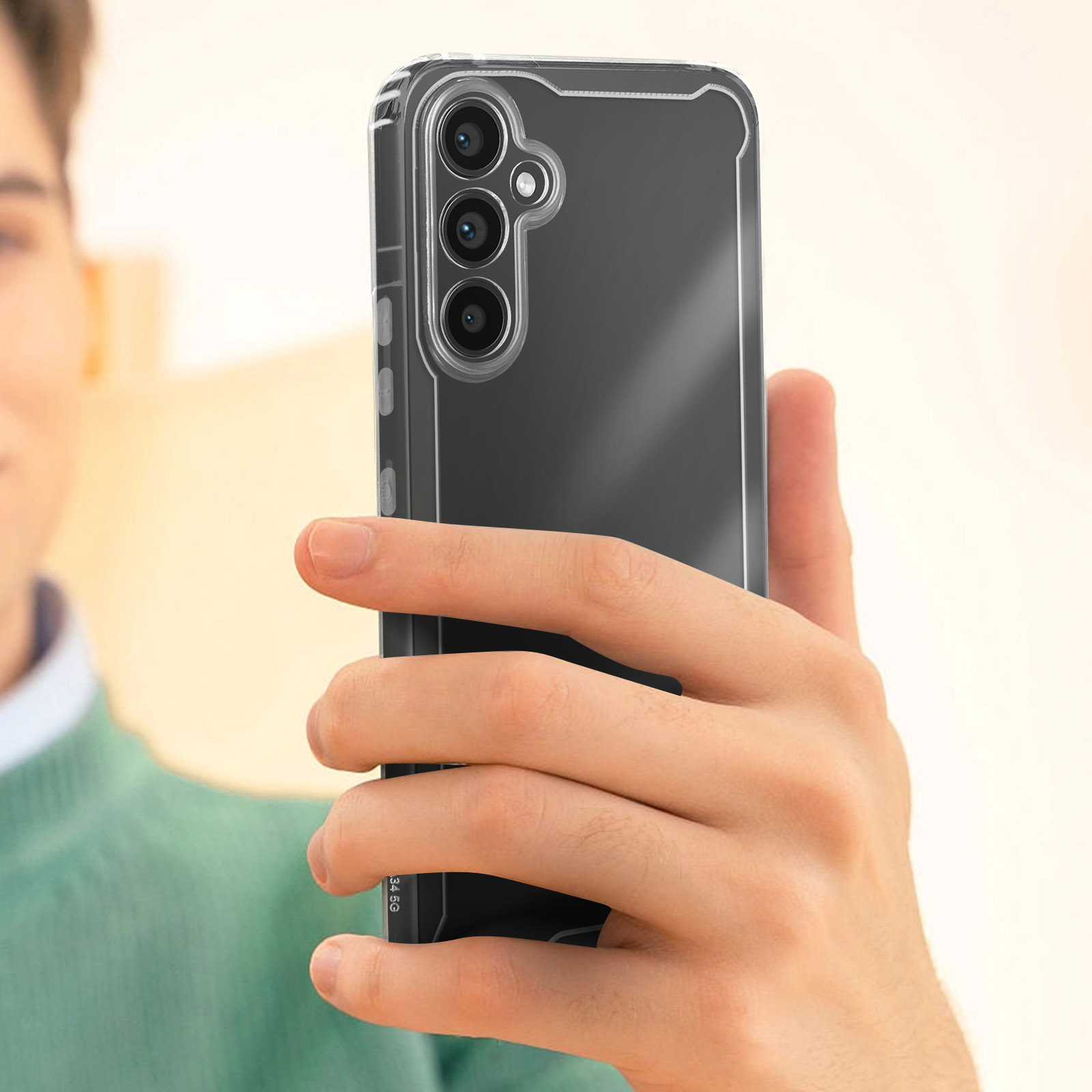 Una persona tiene in mano un telefono in una custodia trasparente. Il telefono ha uno schermo nero e tre fotocamere posteriori.