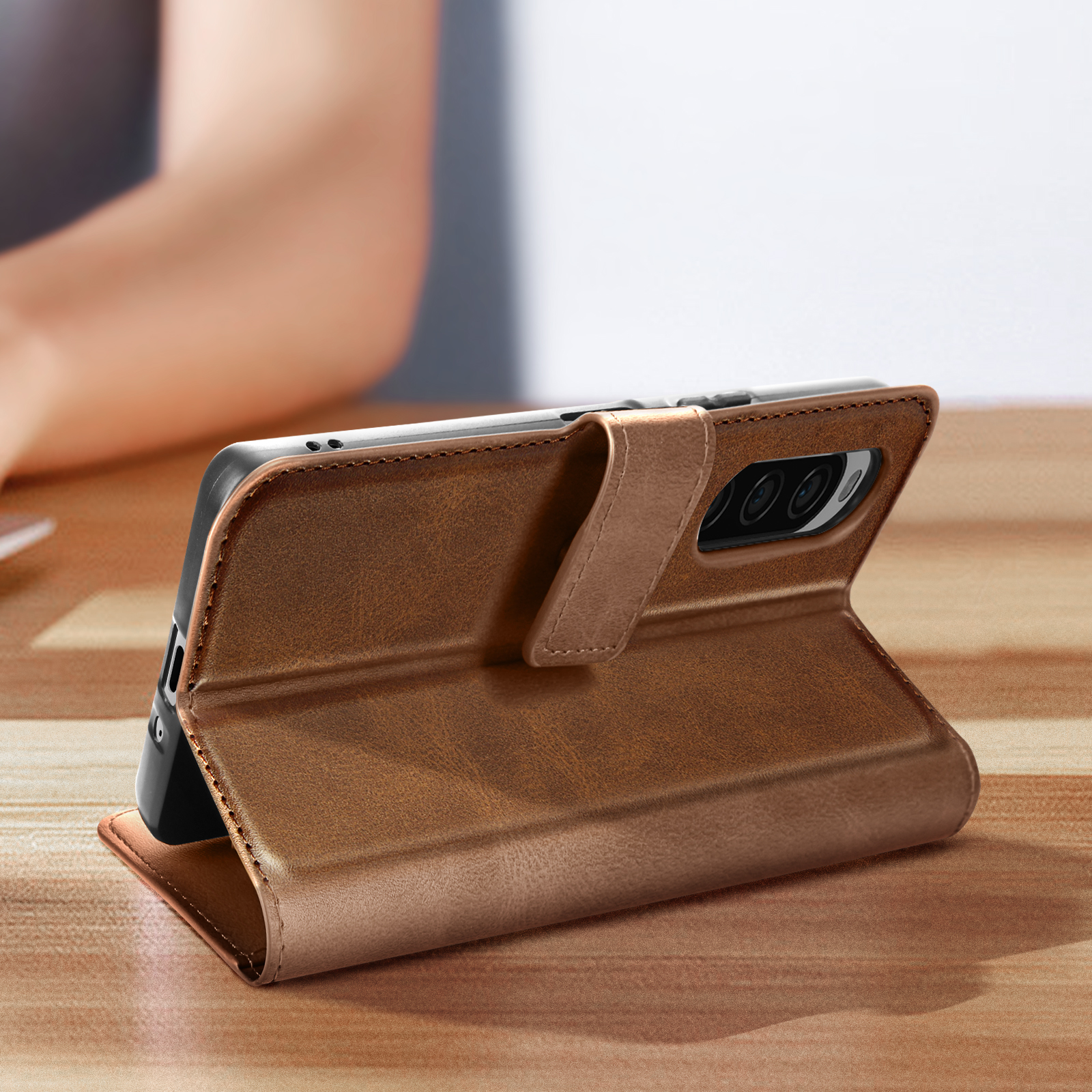 Eine braune Leder-Handyhülle, geöffnet, mit einem Telefon darin. Die Hülle liegt auf einem Tisch.